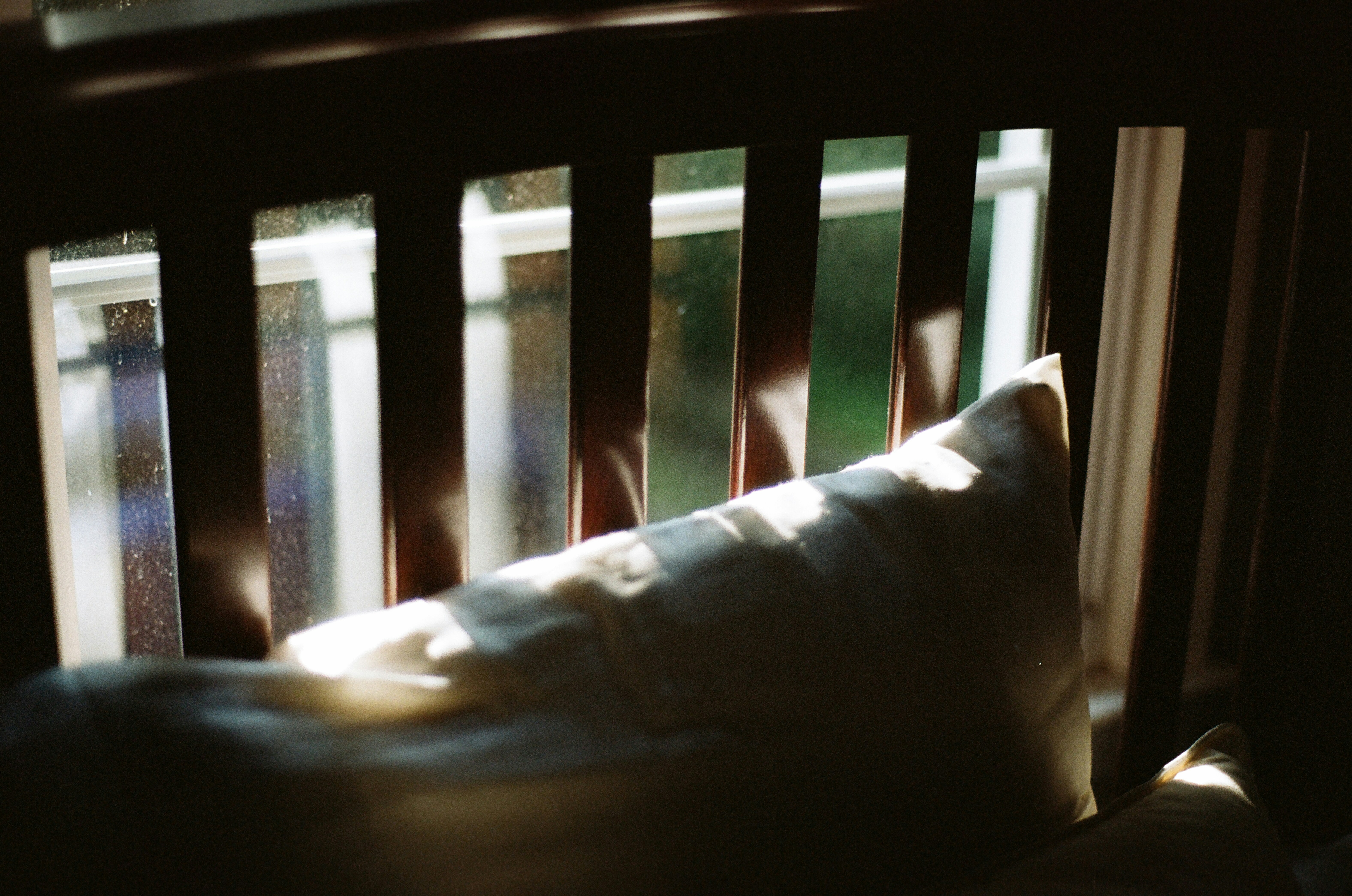 Sunlight streams through wooden slats onto a pillow.