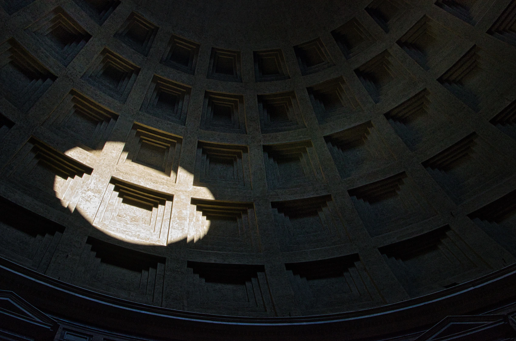 A shaft of sunlight entering through the oculus of the Pantheon's coffered dome in Rome