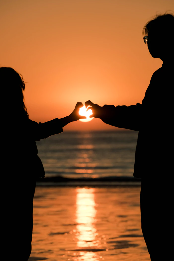Manos formando un corazón al atardecer