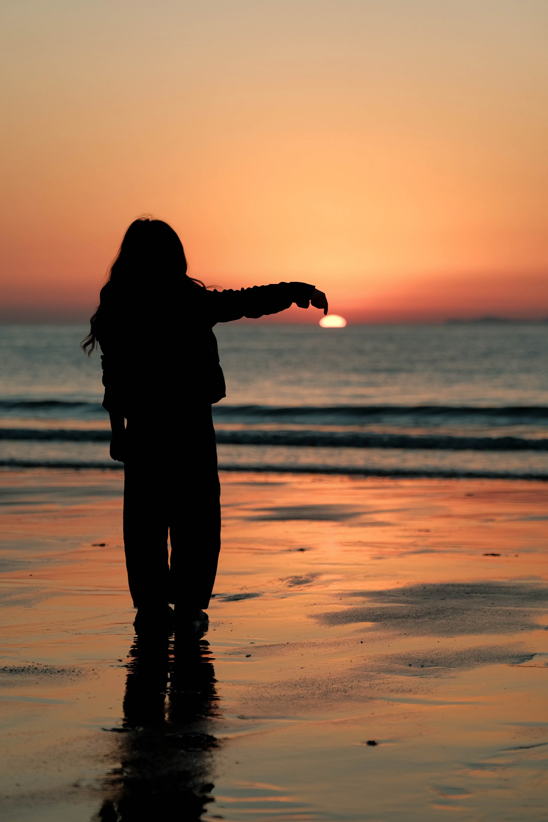 Child silhouetted at sunset holding the sun