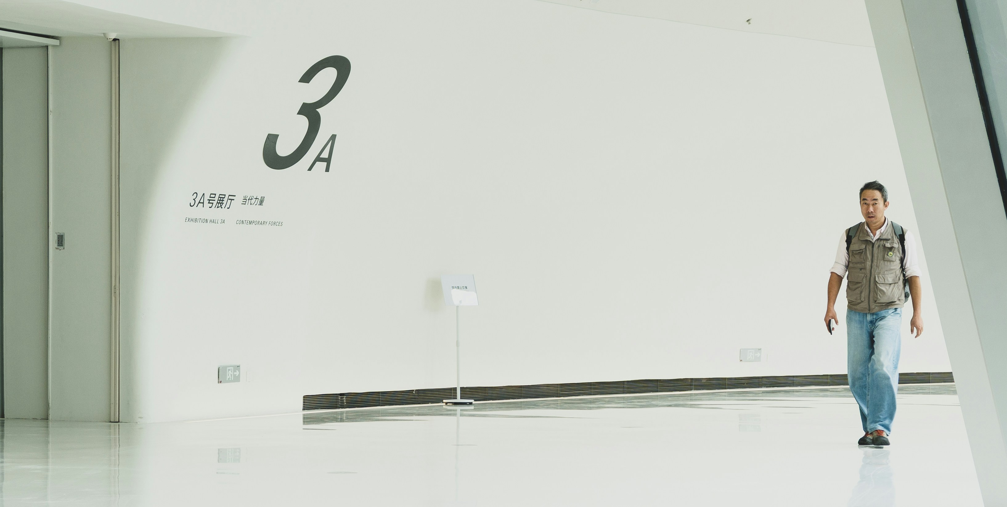 Man walks down a modern hallway with large white walls.