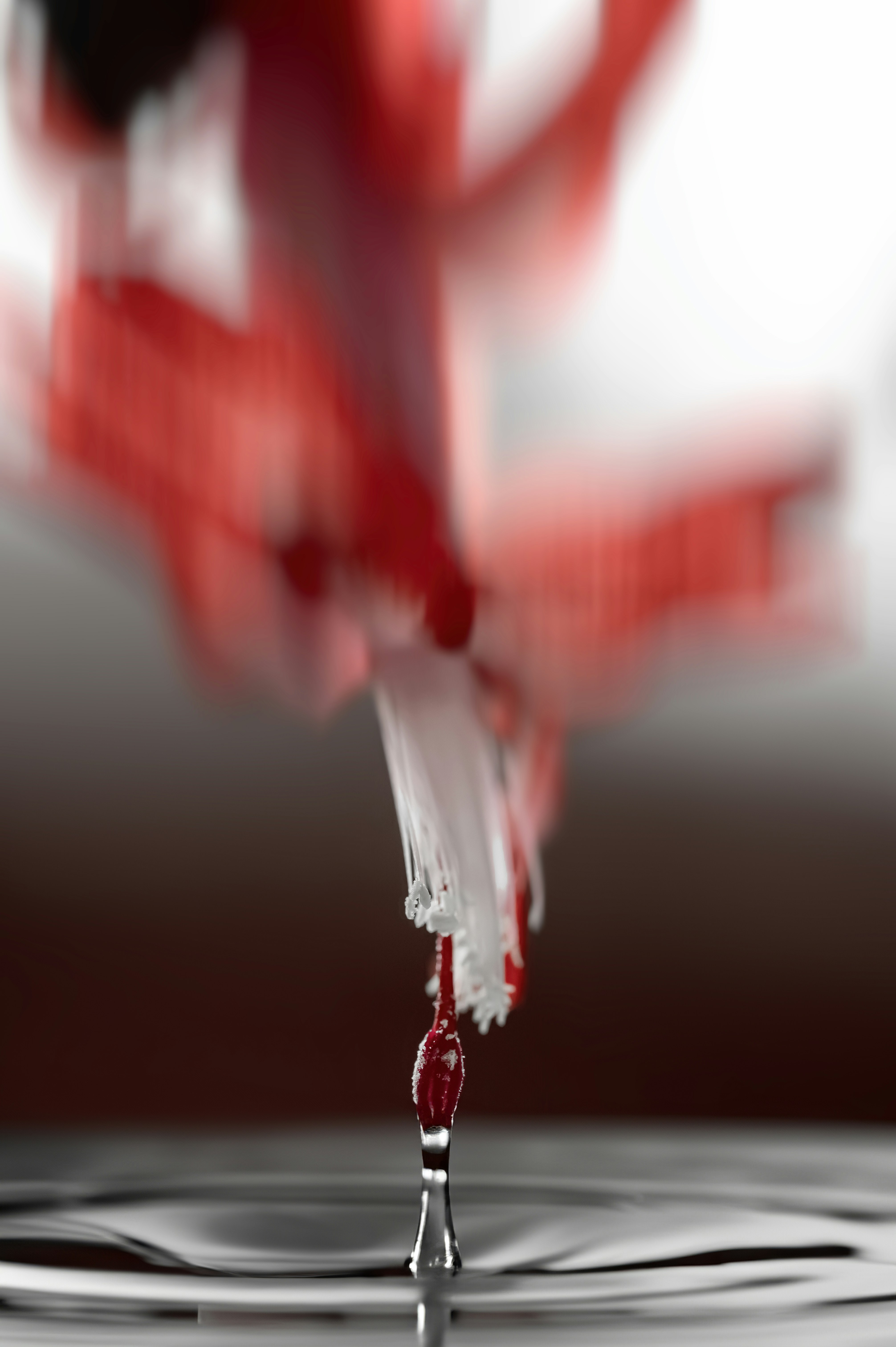 Red liquid dripping into water, blurred background