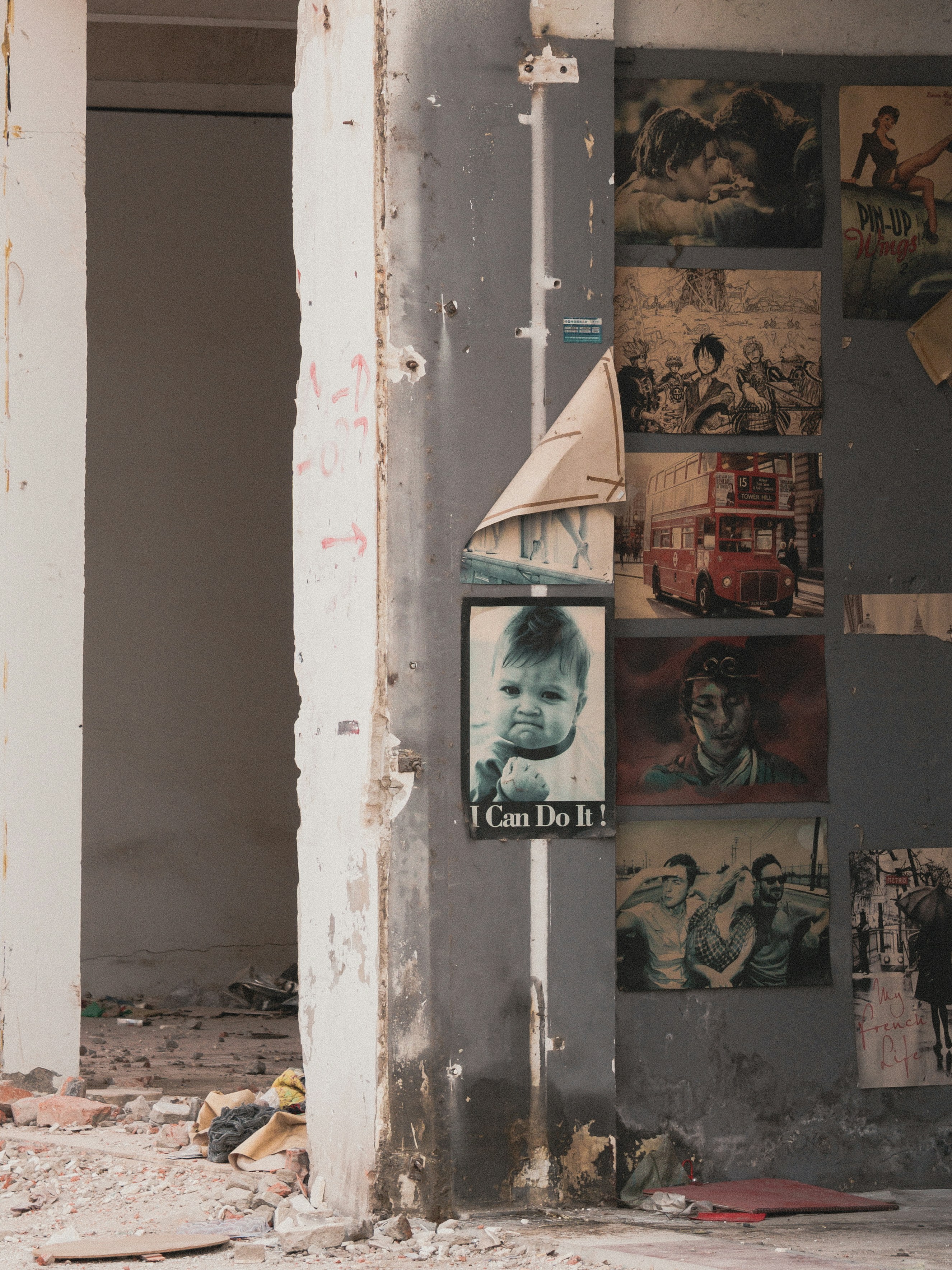 Collection of vintage posters on a damaged wall.