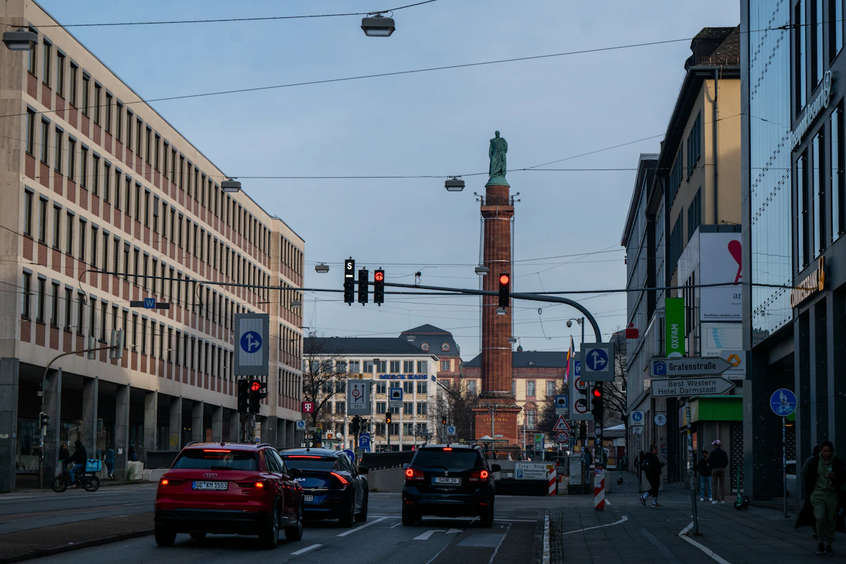 Cars driving on a city street with buildings and tower.