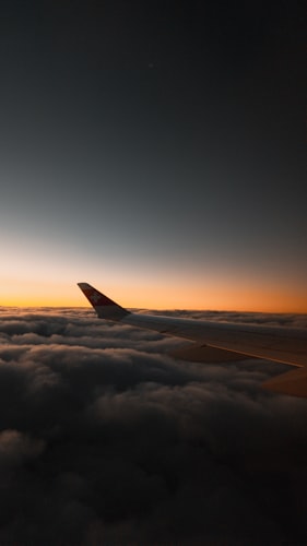 Airplane wing above clouds at sunset