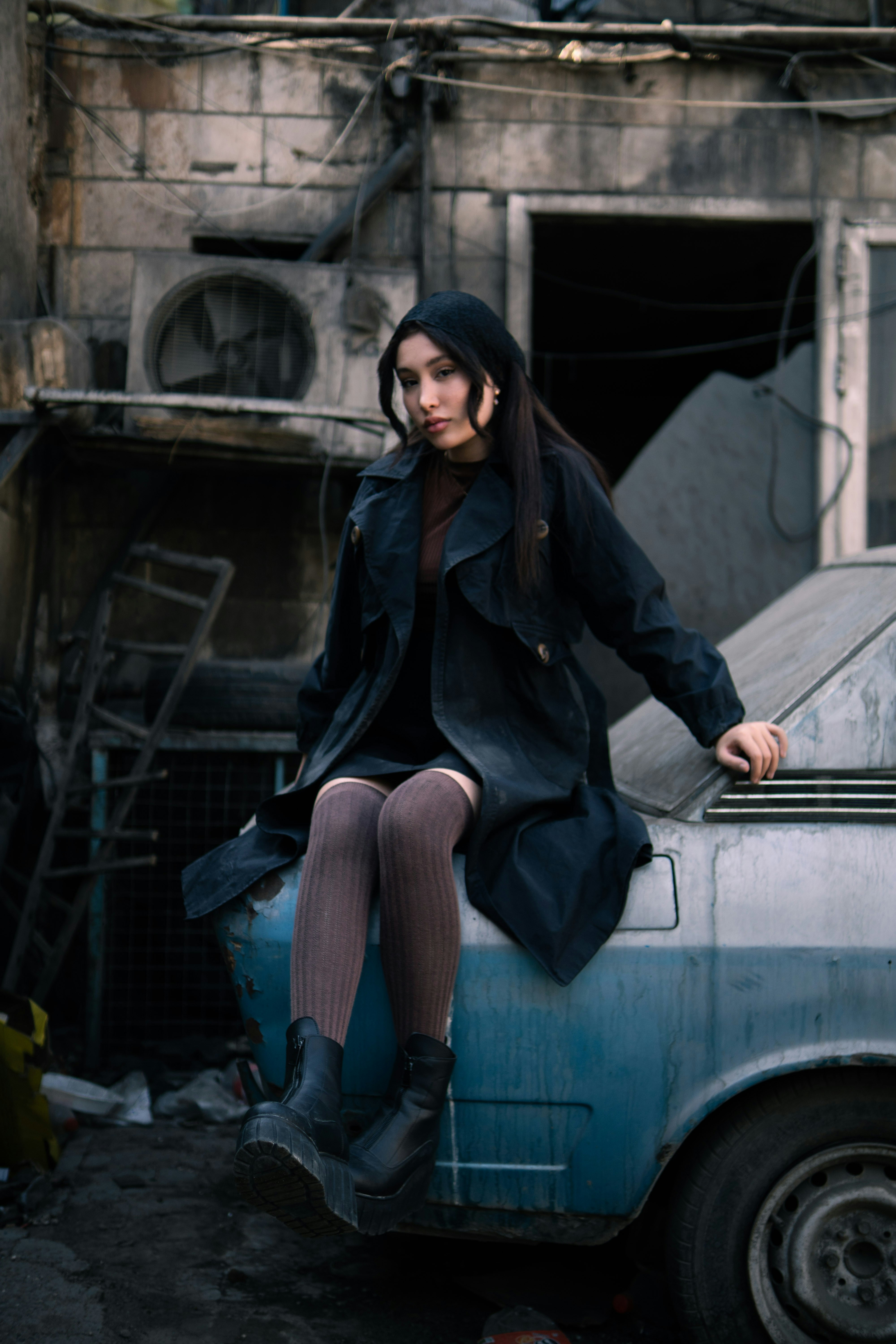 Young woman sits on a derelict car