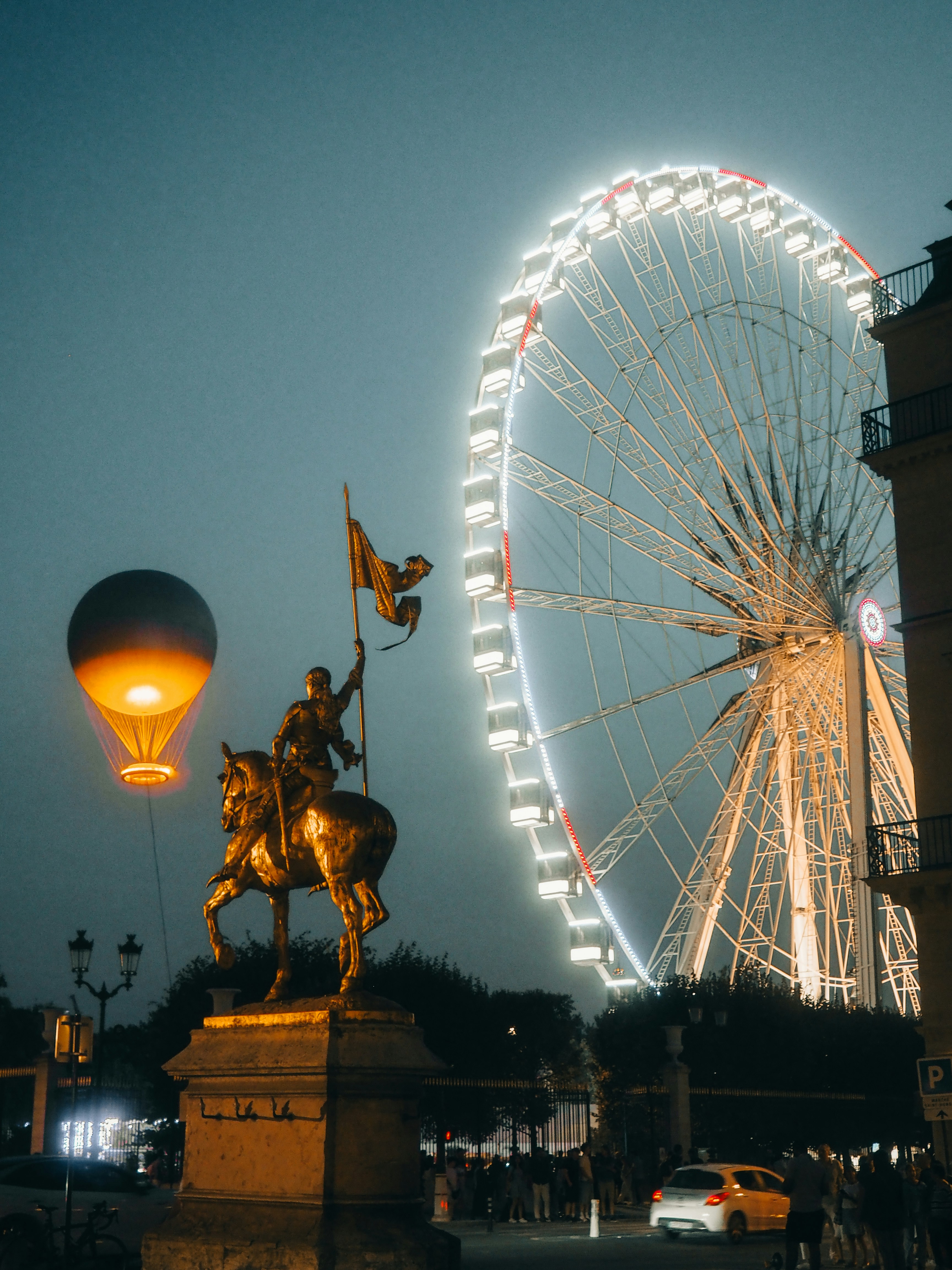 Statue and hot air balloon with ferris wheel at night