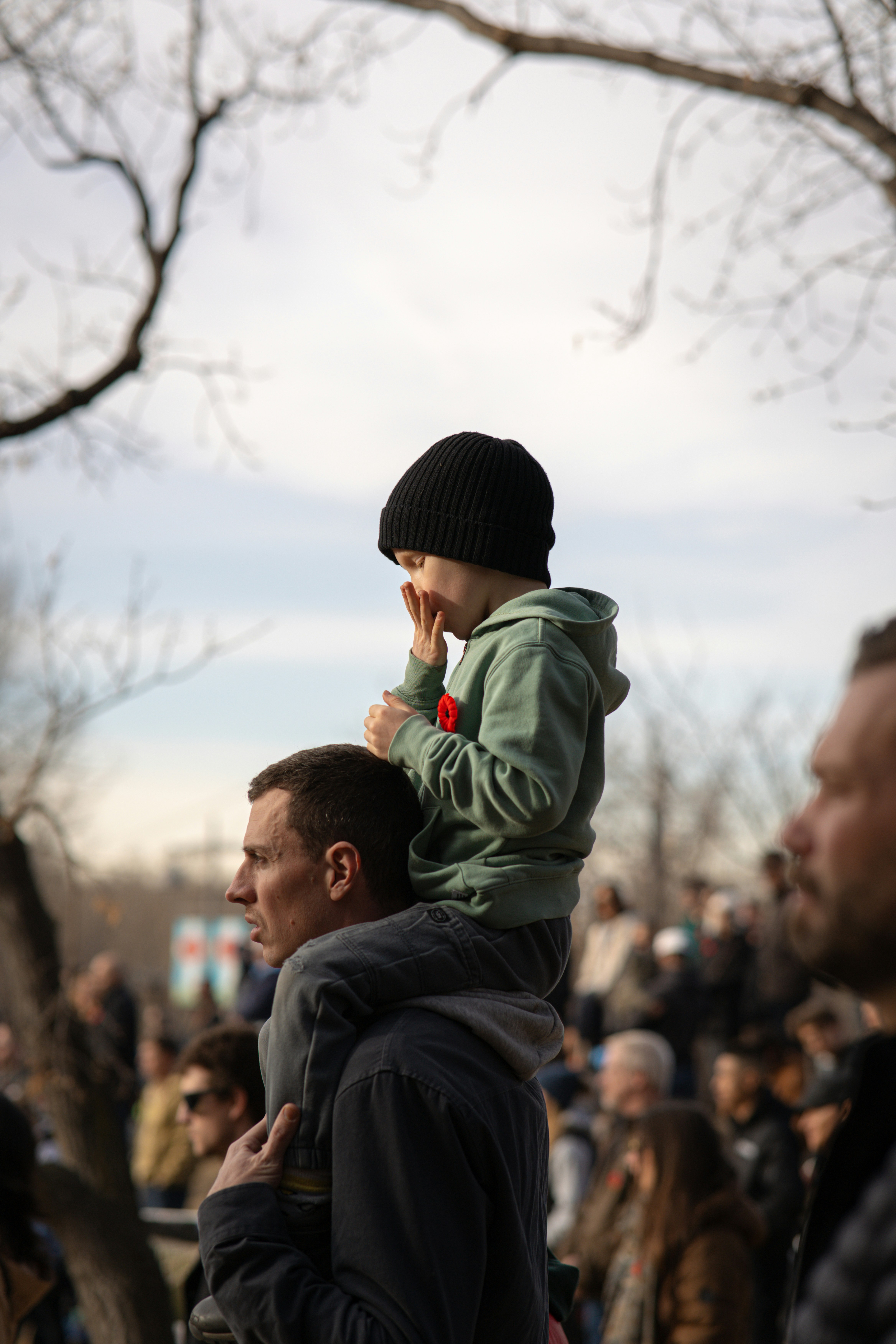 Pai carrega criança nos ombros em evento ao ar livre