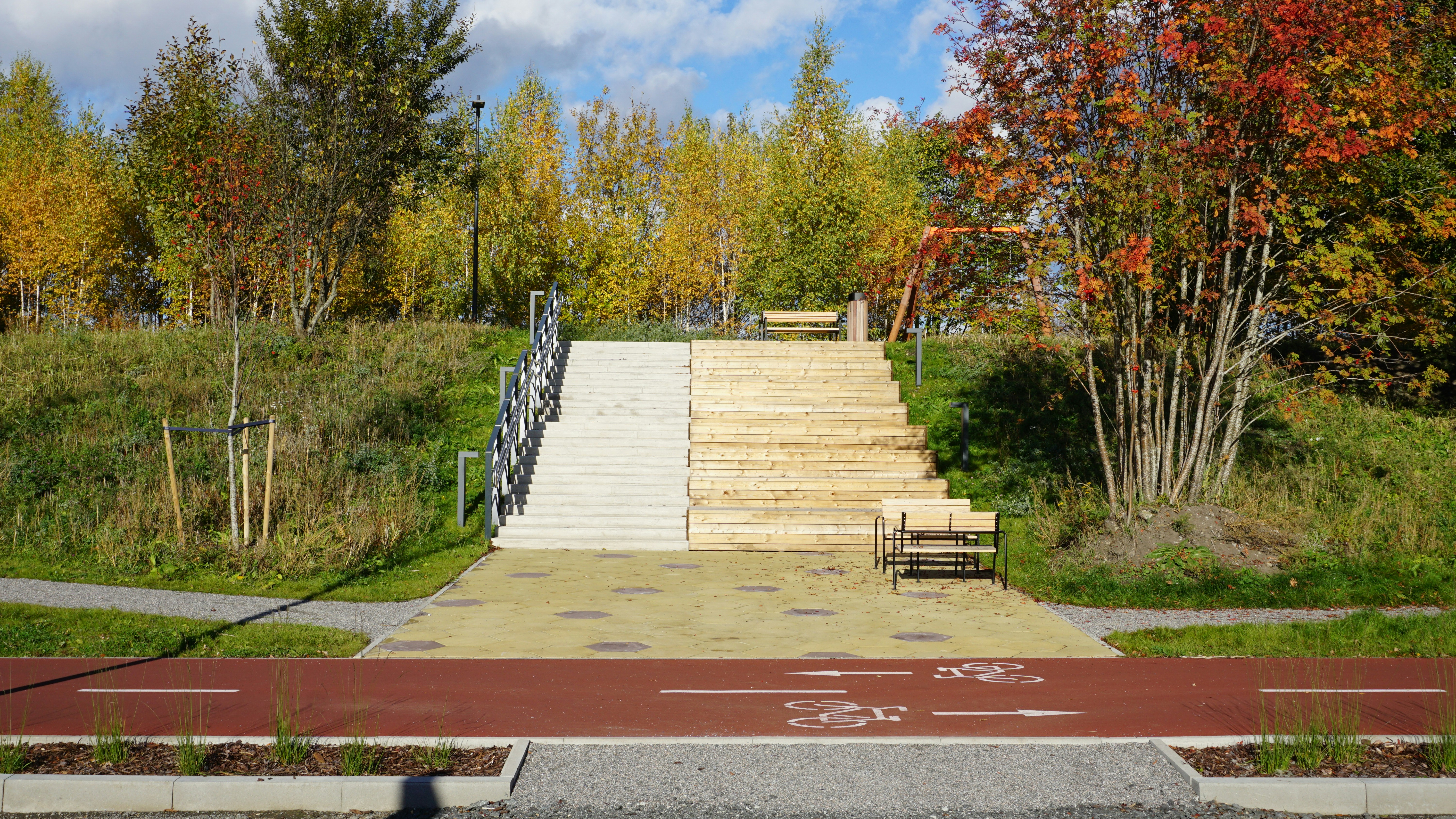 Wooden stairs leading up a grassy hill with autumn trees