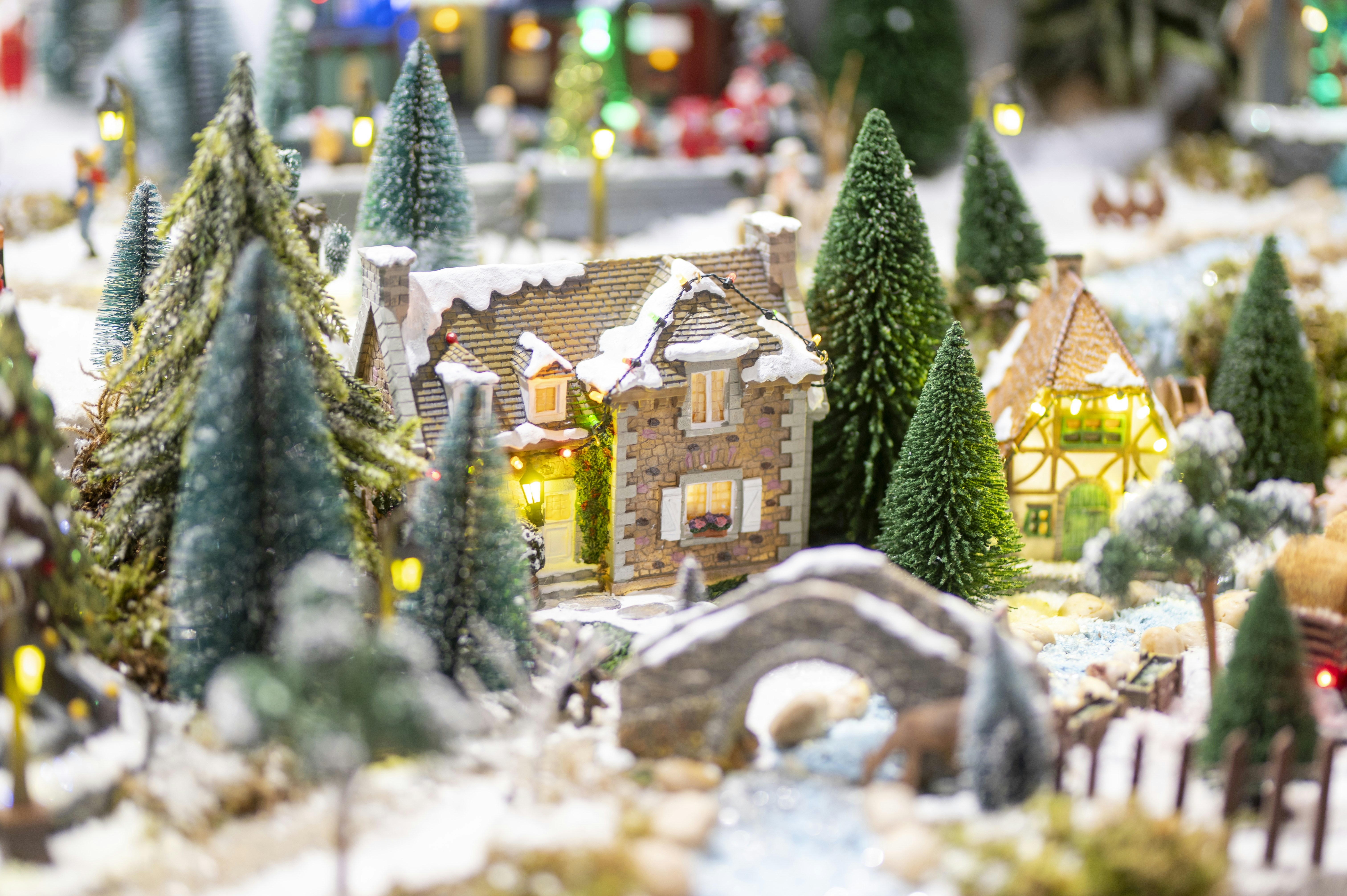 Miniature snowy village with illuminated houses and trees.