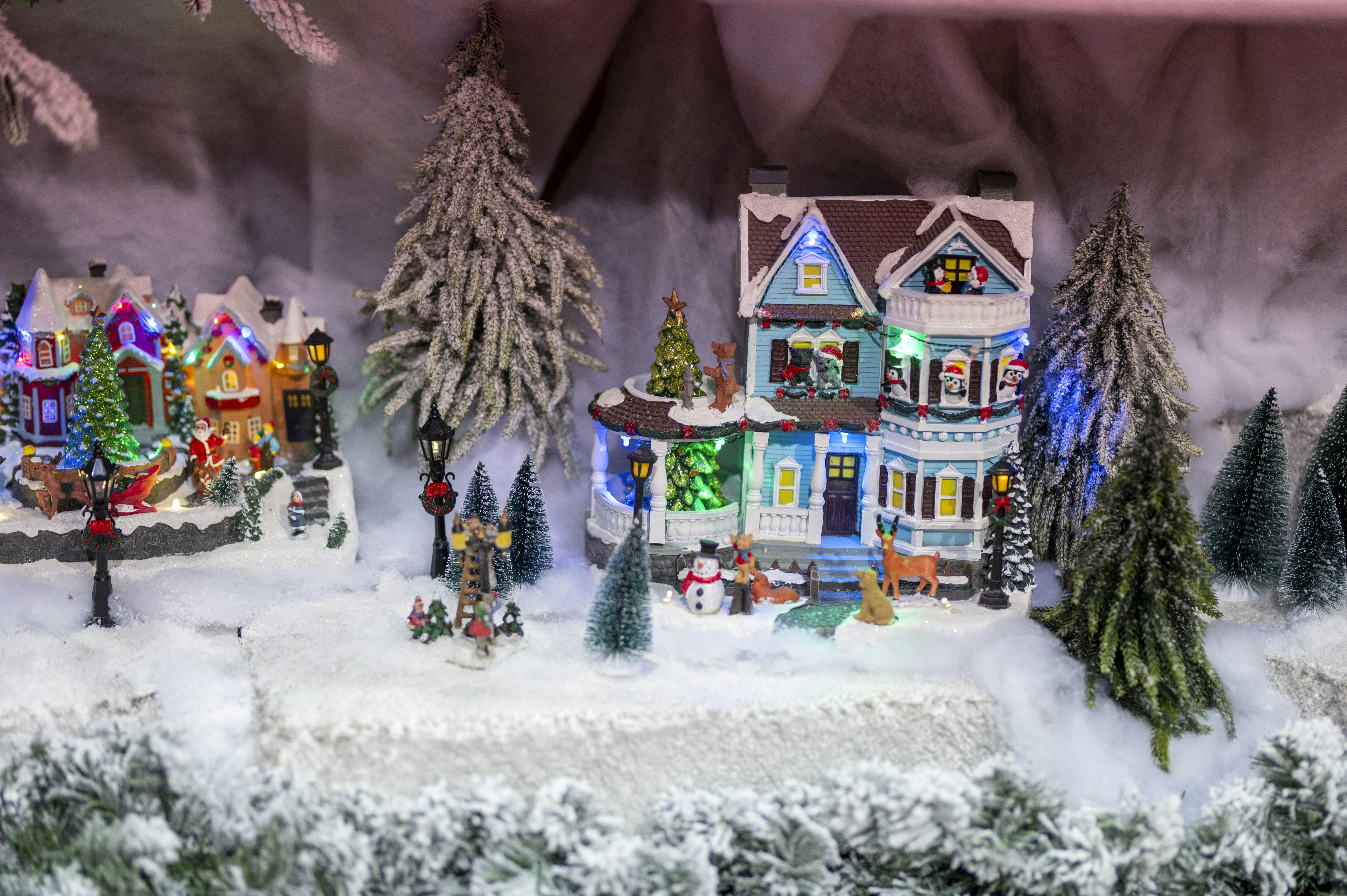 Festive miniature village with snow and christmas lights.