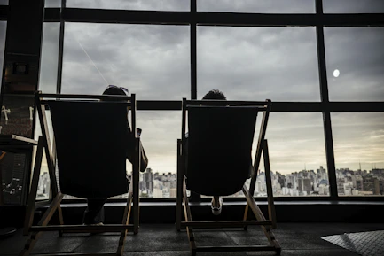 Two people sit in chairs looking out window