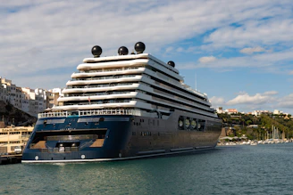 A large dark blue cruise ship docked in a harbor.