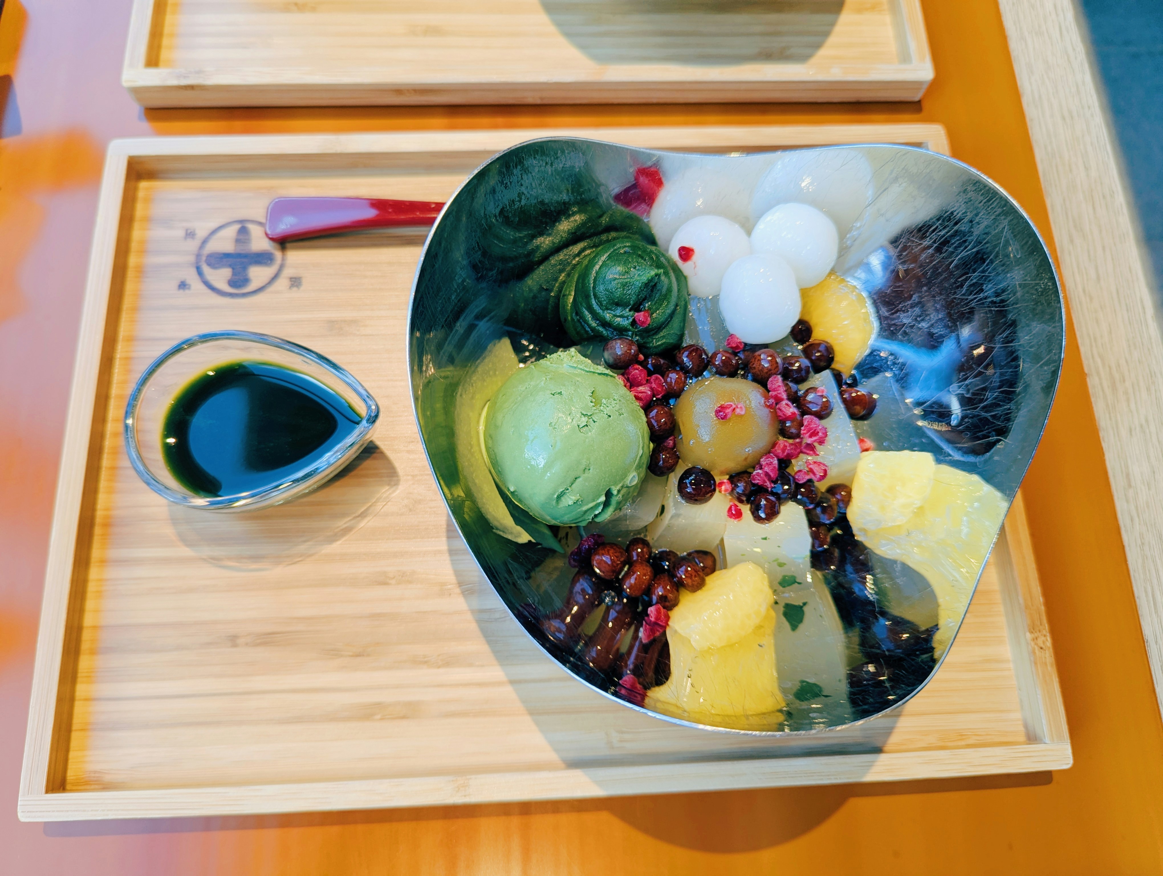 Dessert with ice cream, fruits, and beans on a tray