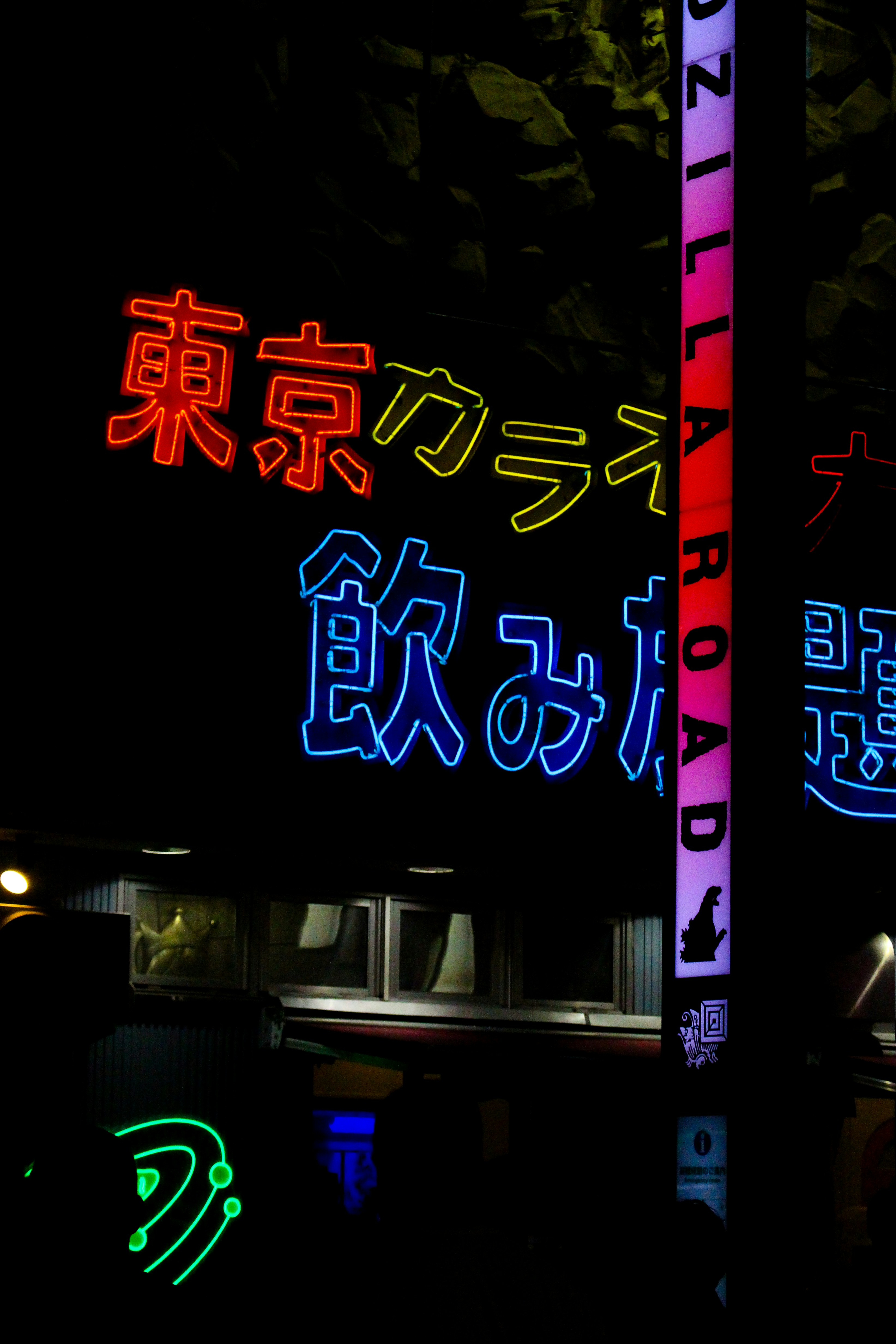 Los carteles de neón iluminan una calle oscura de la ciudad por la noche.