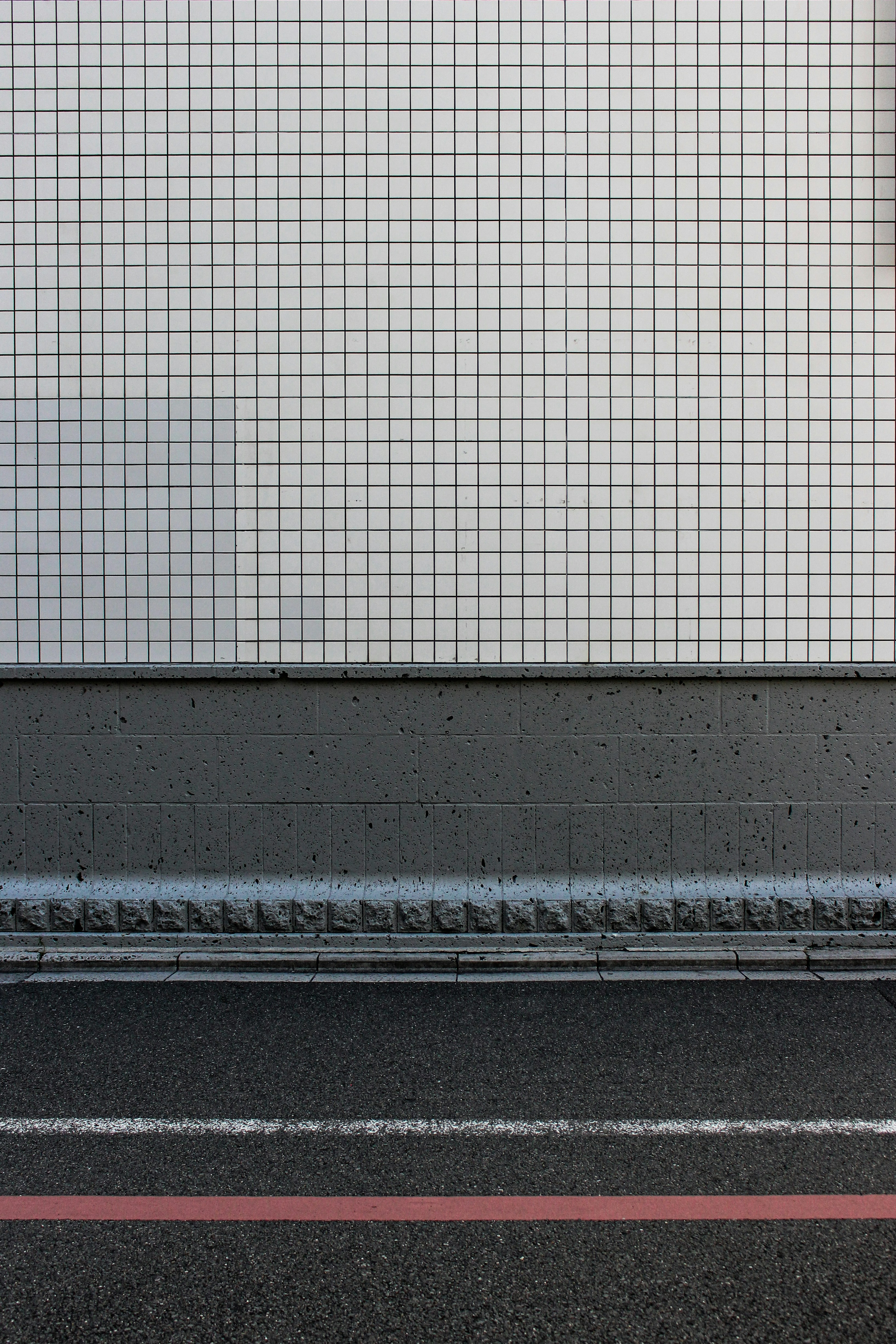 Pared de baldosas blancas sobre hormigón oscuro y asfalto