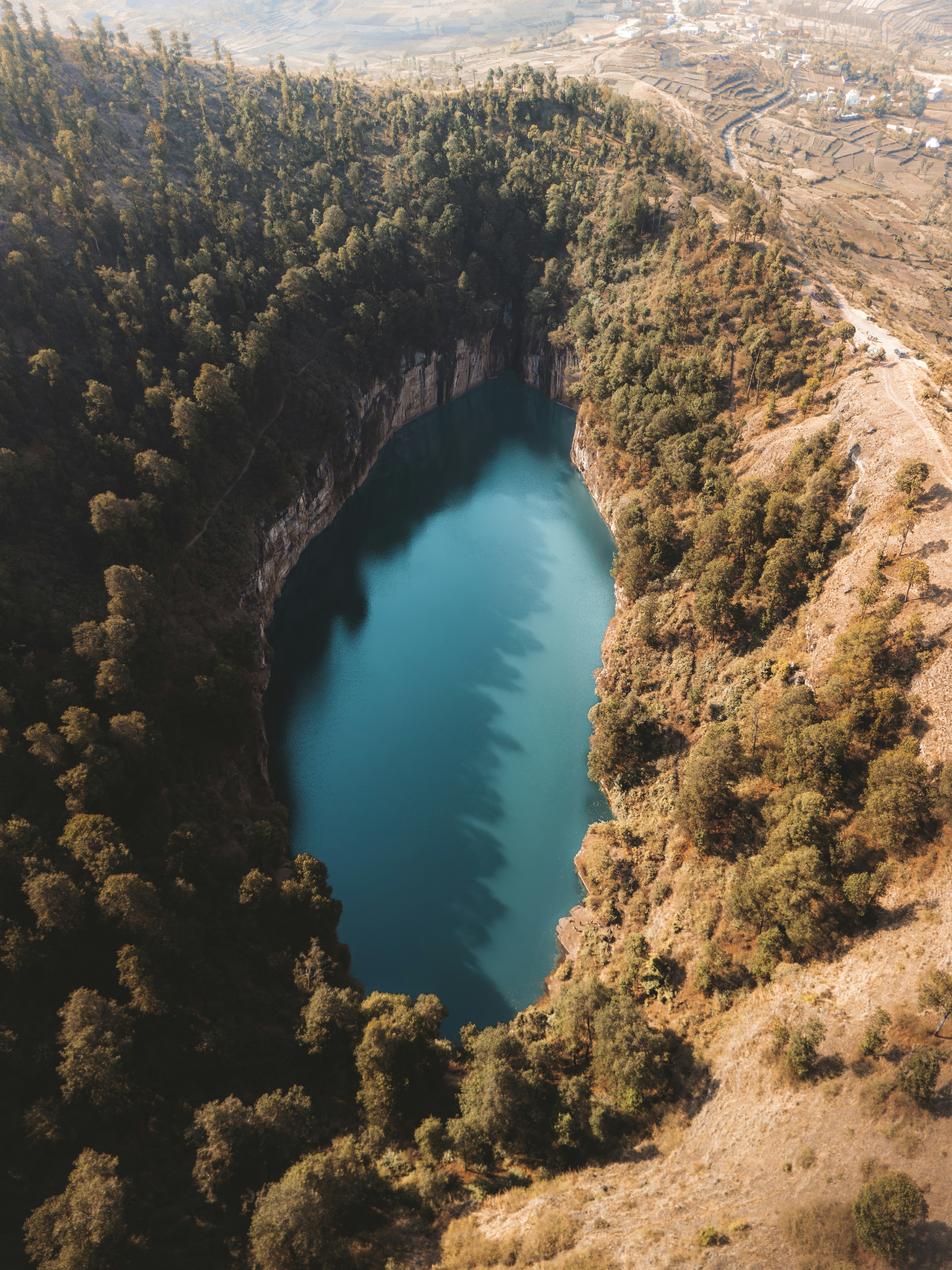 Photo of Aerial view of a vibrant blue lake surrounded by forest. by Guillaume Auceps