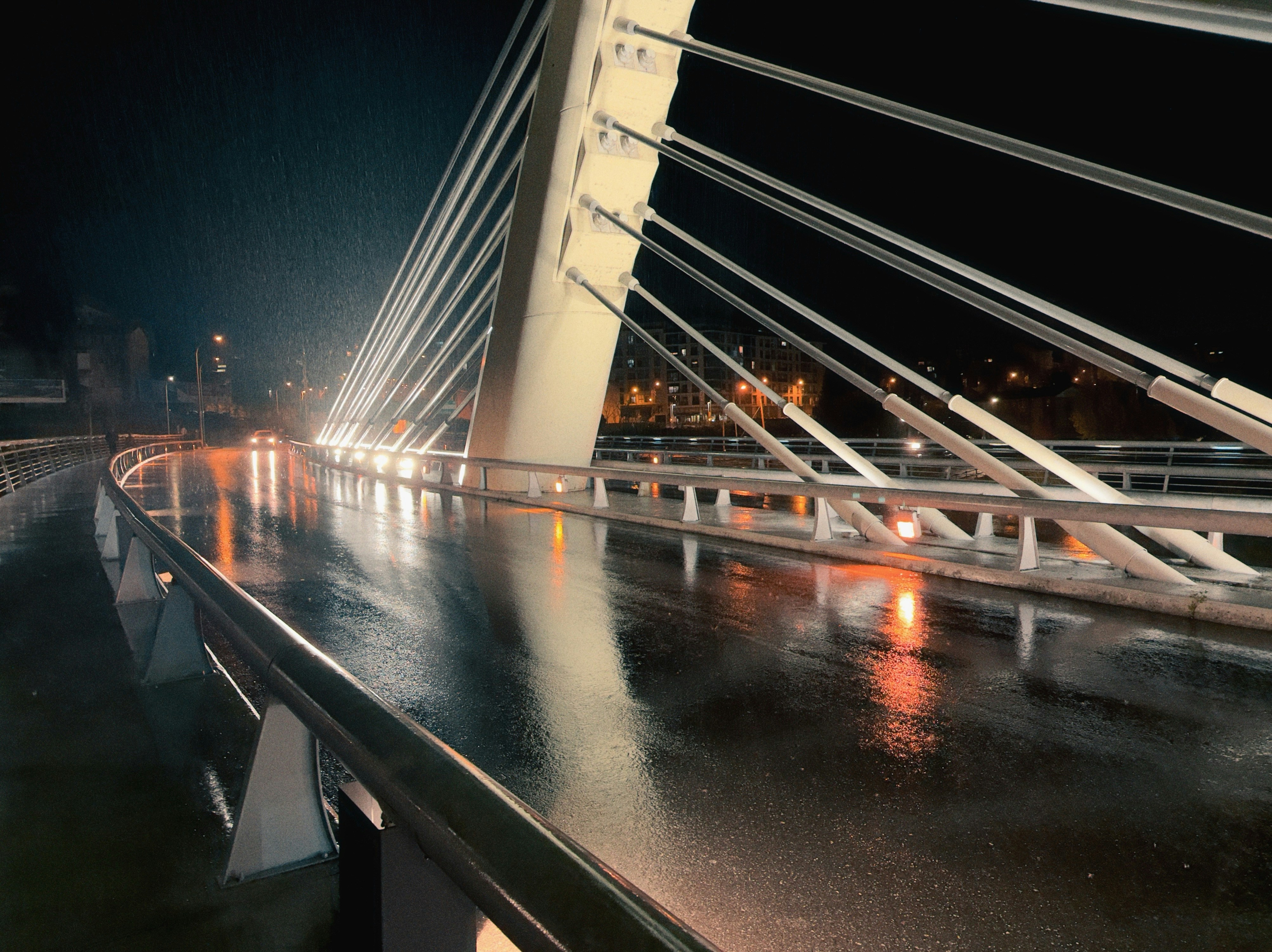 Wet bridge at night with city lights reflected