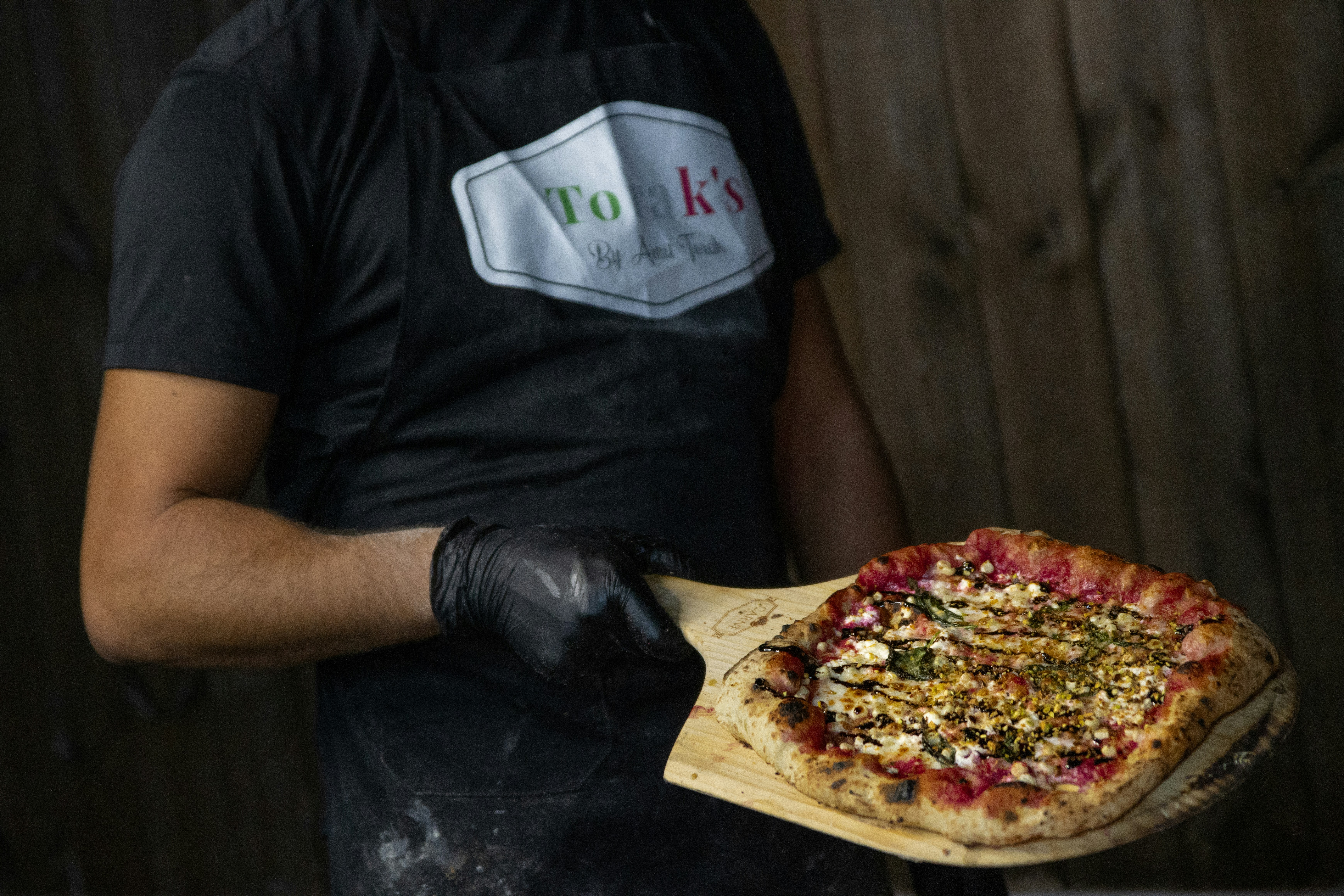 Chef holding a freshly baked pizza on a peel.