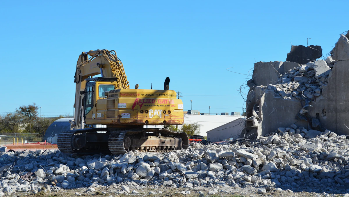 Pelle mécanique jaune en train de démolir une structure en béton sur chantier