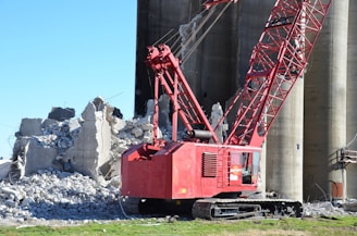 Red crane next to demolished concrete structure