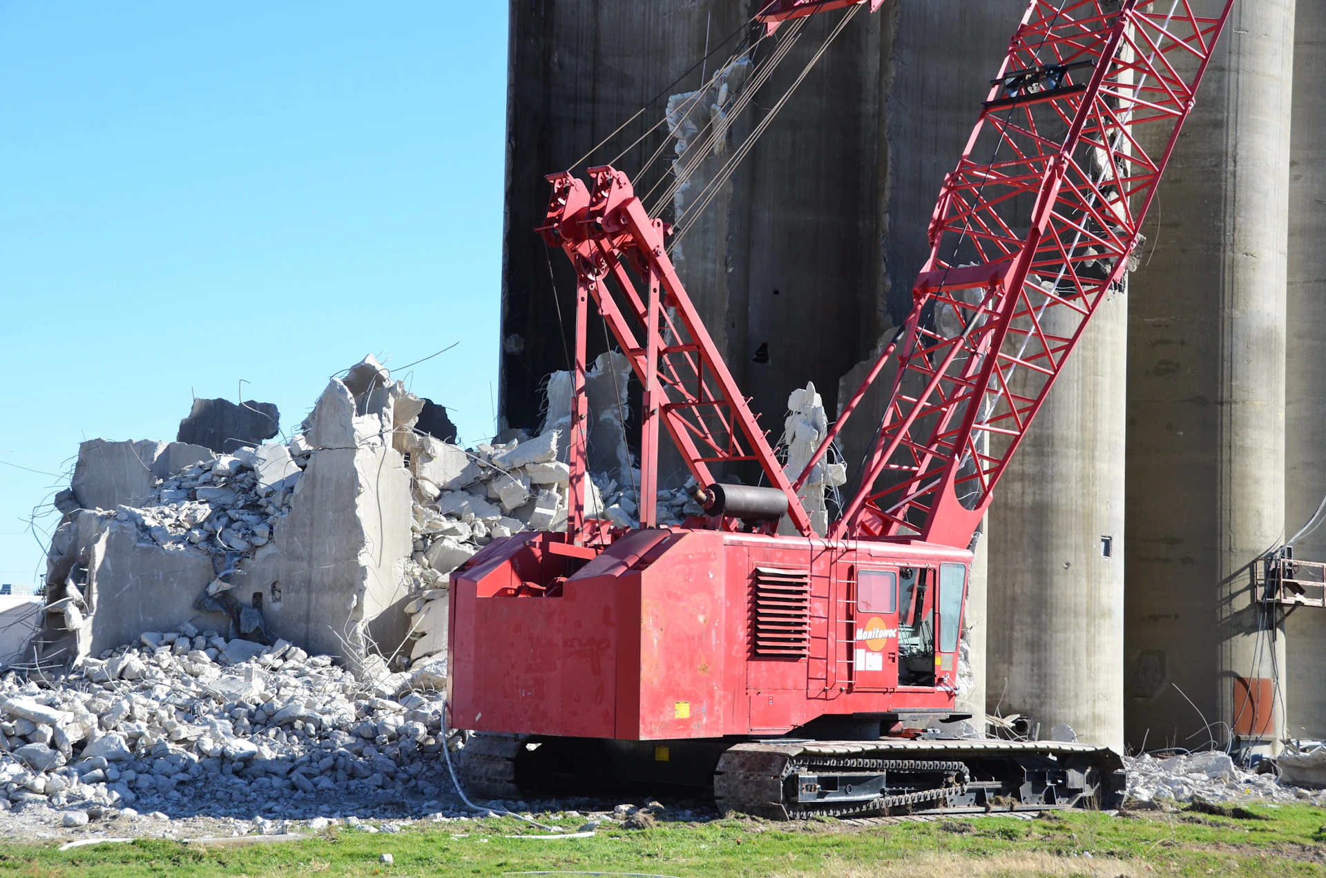 Red crane next to demolished concrete structure