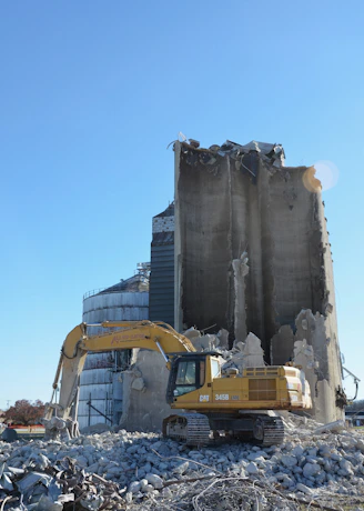 Excavator demolishing a concrete silo structure