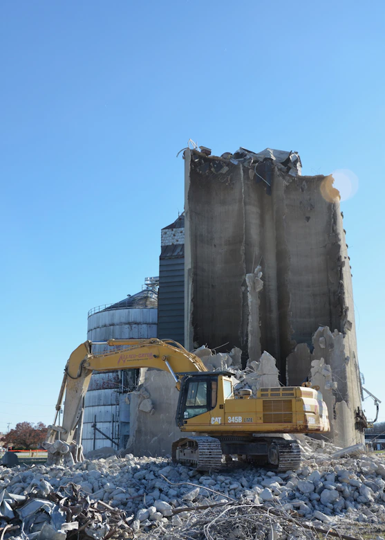 Excavator demolishing a concrete silo structure