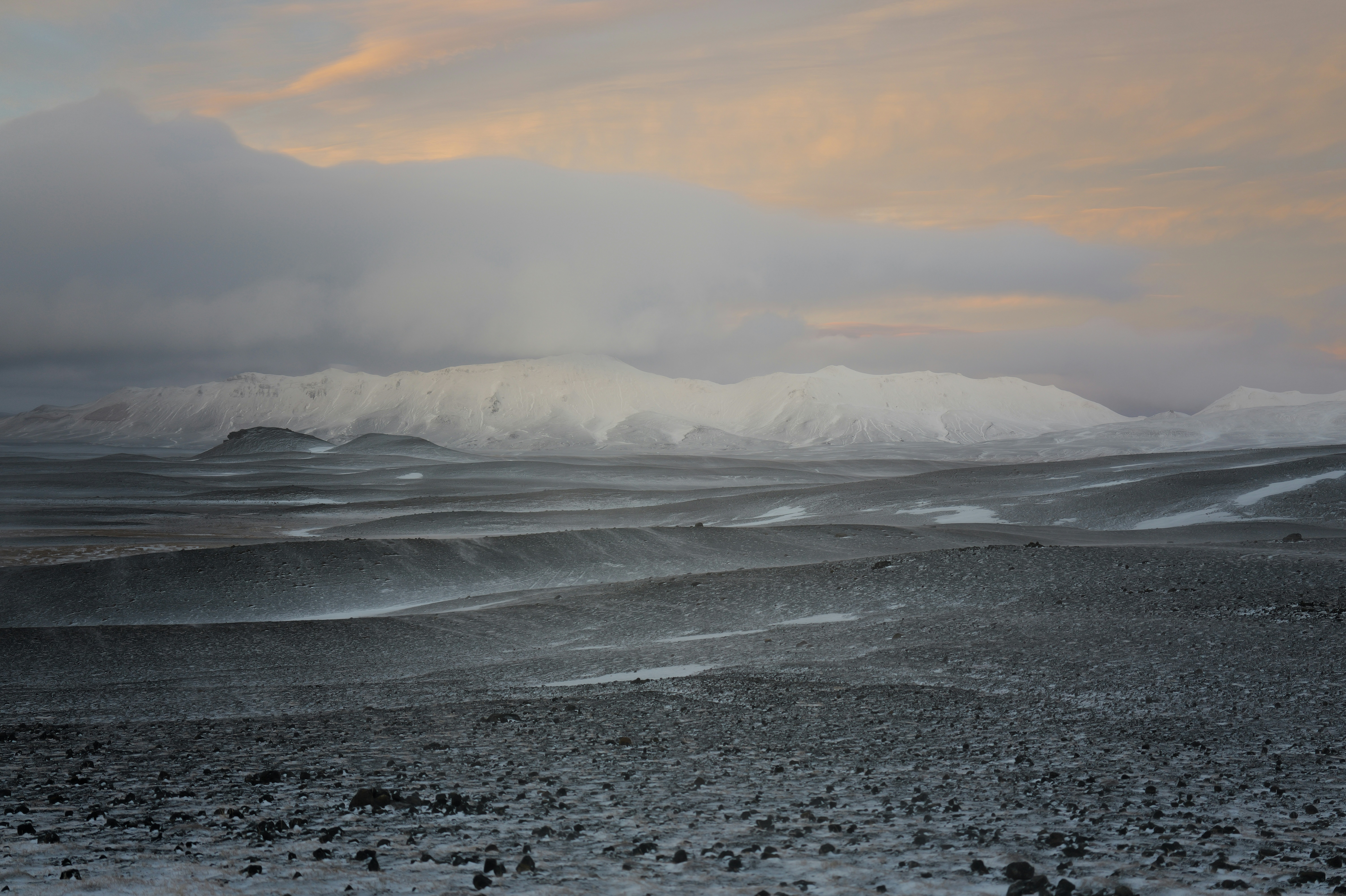 Snowy landscape with mountains under cloudy sky