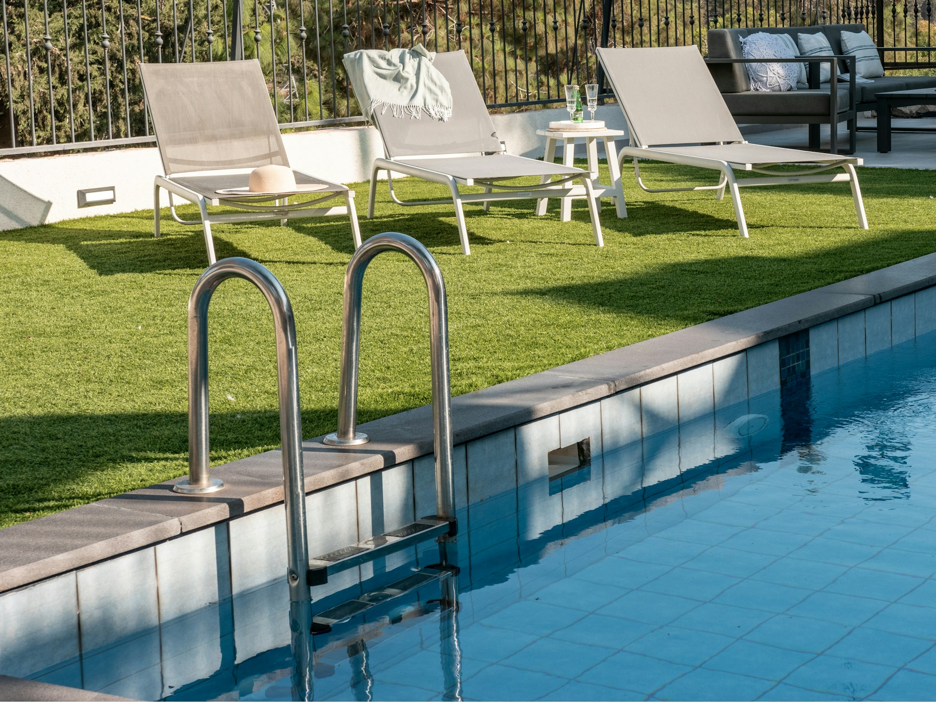 Lounge chairs by a swimming pool on a sunny day.