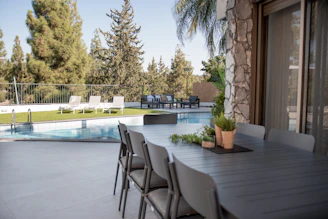 Outdoor dining table and chairs by a swimming pool.