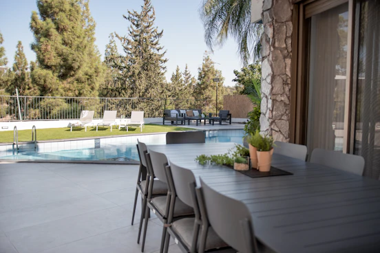 Outdoor dining table and chairs by a swimming pool.