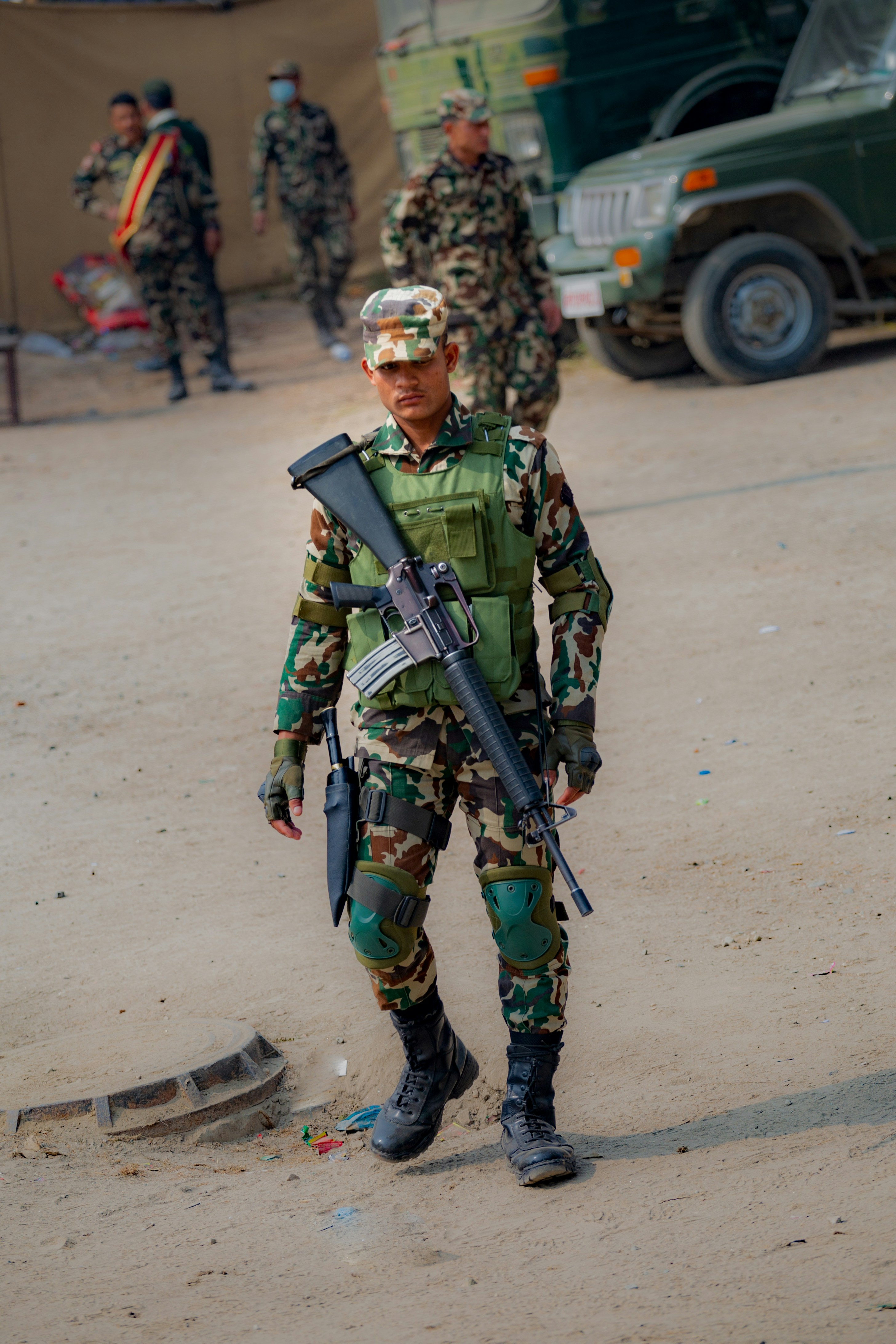 Soldier in camouflage uniform with rifle walks forward.