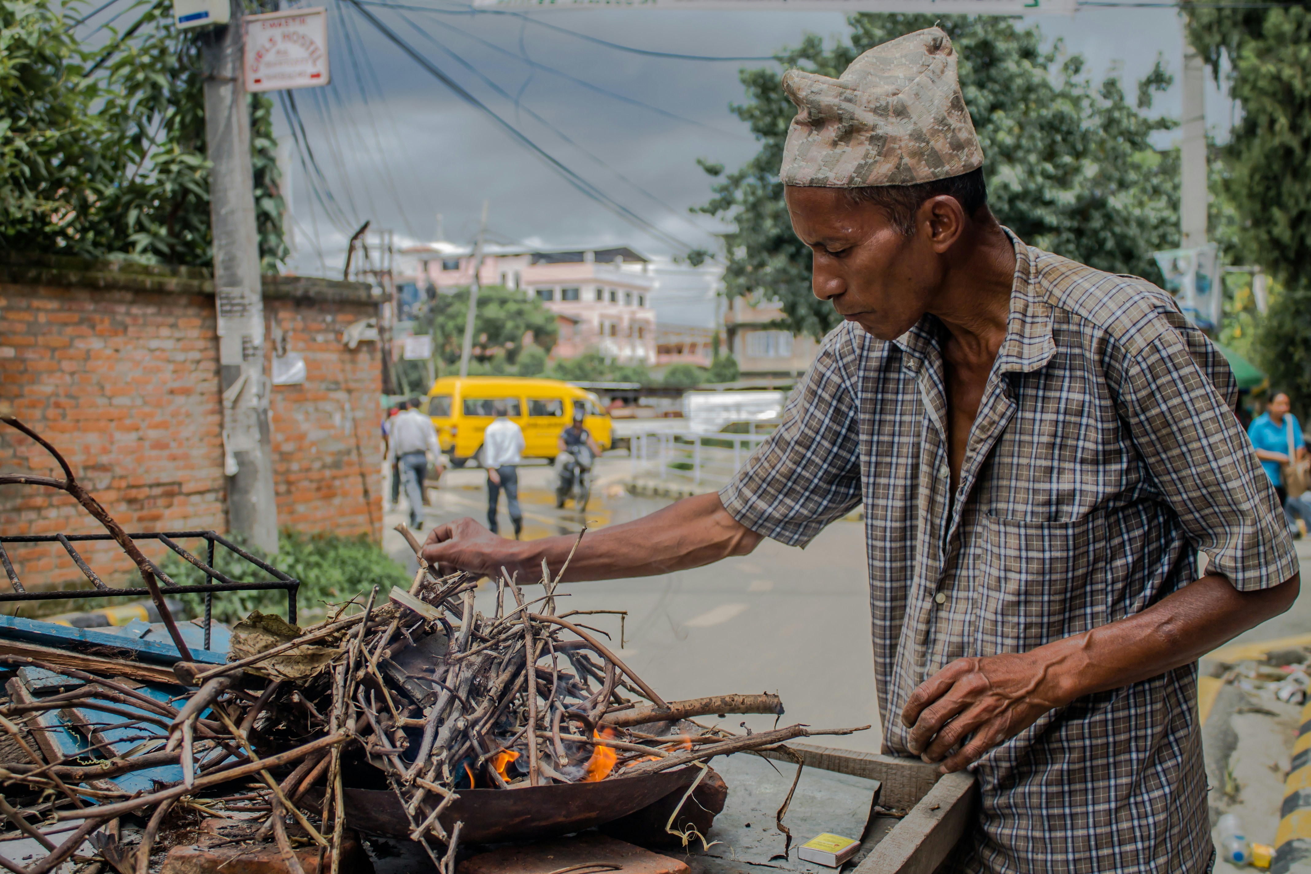 Man tending a fire with sticks on a street.