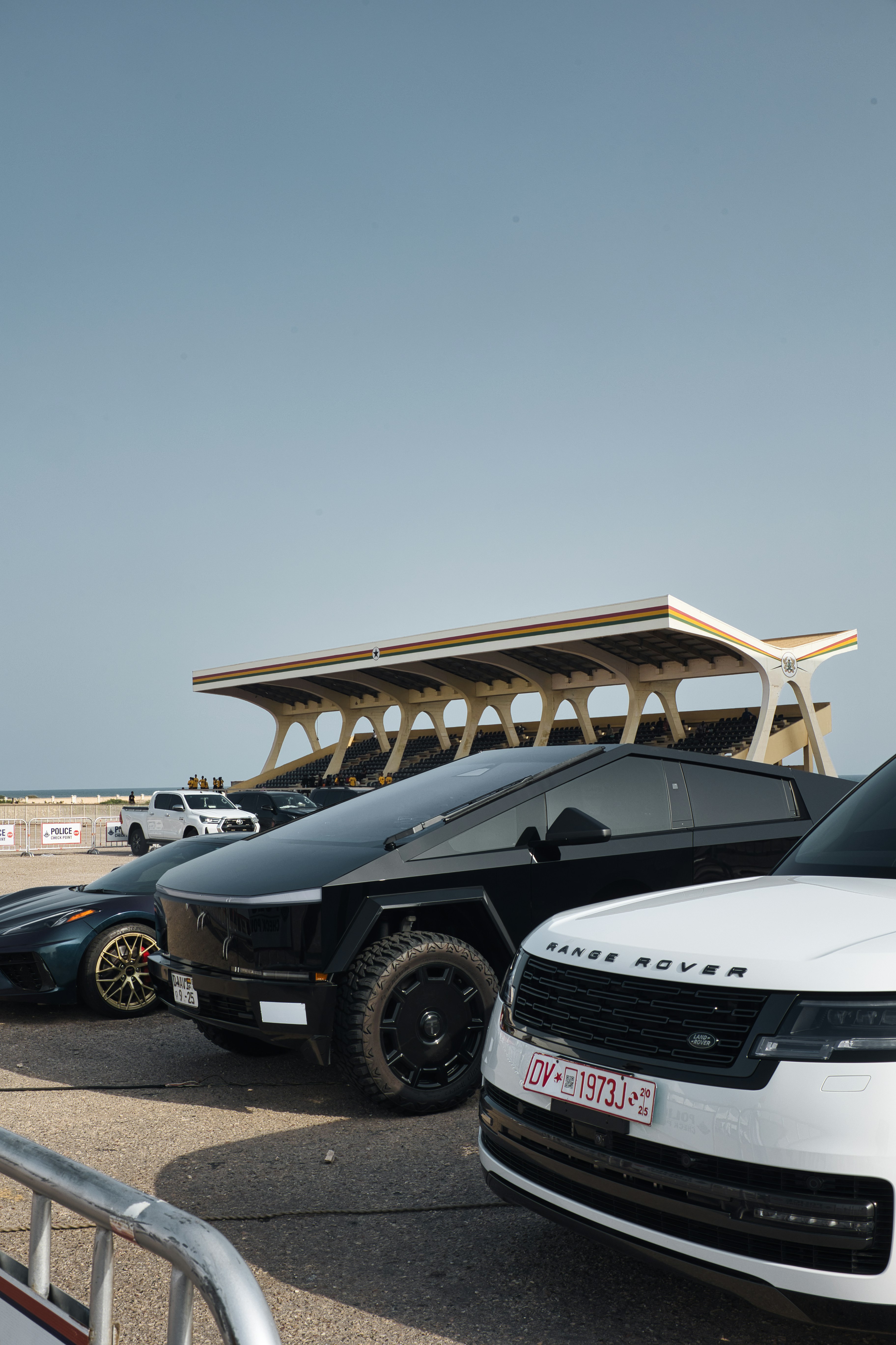 Several luxury cars parked outdoors with stadium in background
