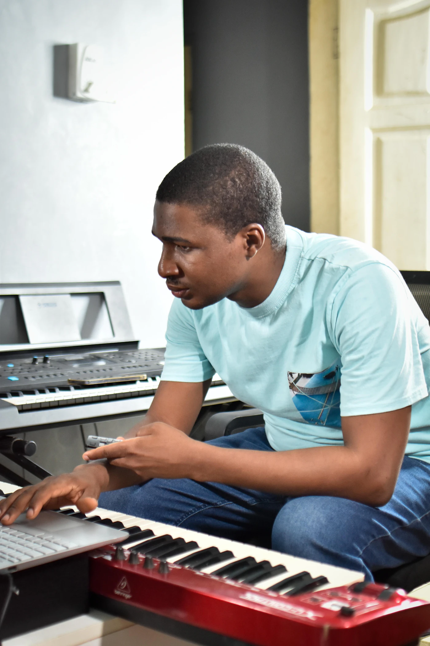 Music producer working with keyboards and a laptop in a studio