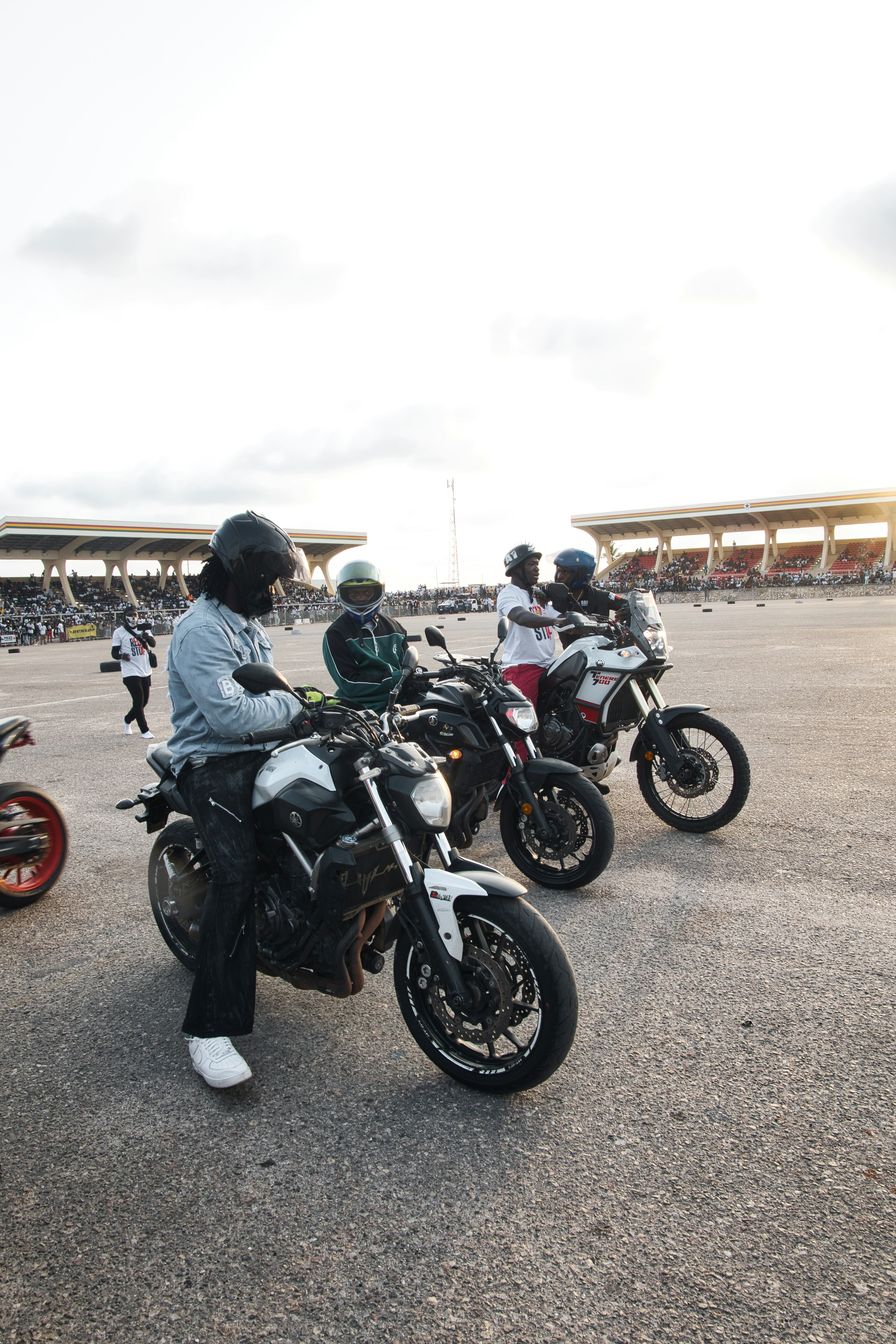 Four people on motorcycles at an outdoor event