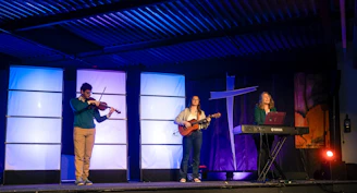 Three musicians performing on a stage with lights.