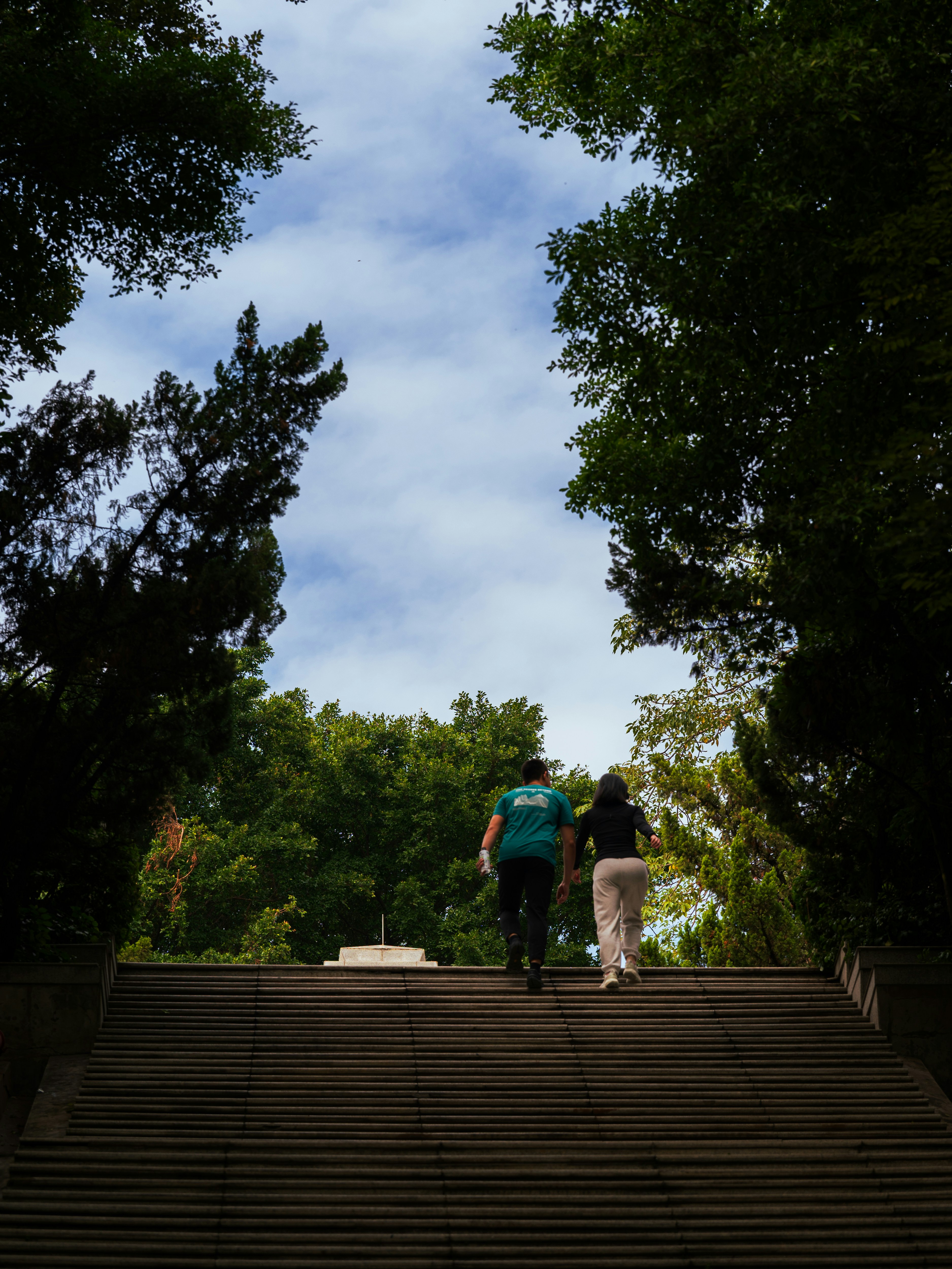 Two people walking up a wide stone staircase.