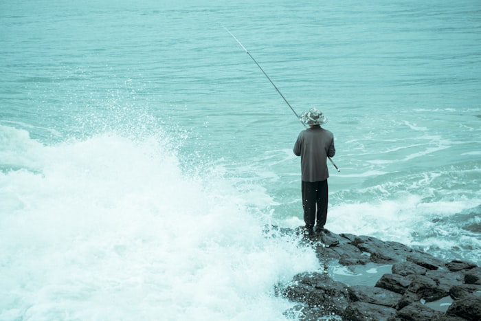 Surf fisherman casting a line into turbulent ocean waves from shore