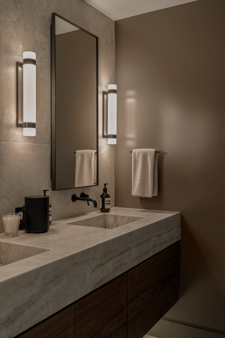 Bathroom vanity with marble countertop and wall sconces