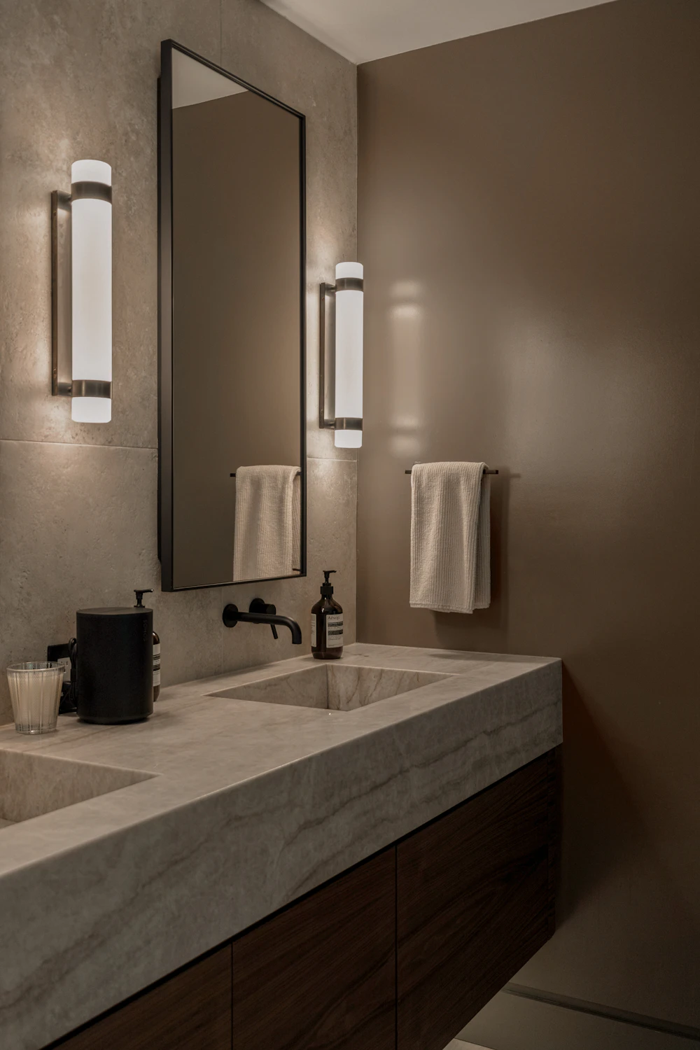 Bathroom vanity with marble countertop and wall sconces
