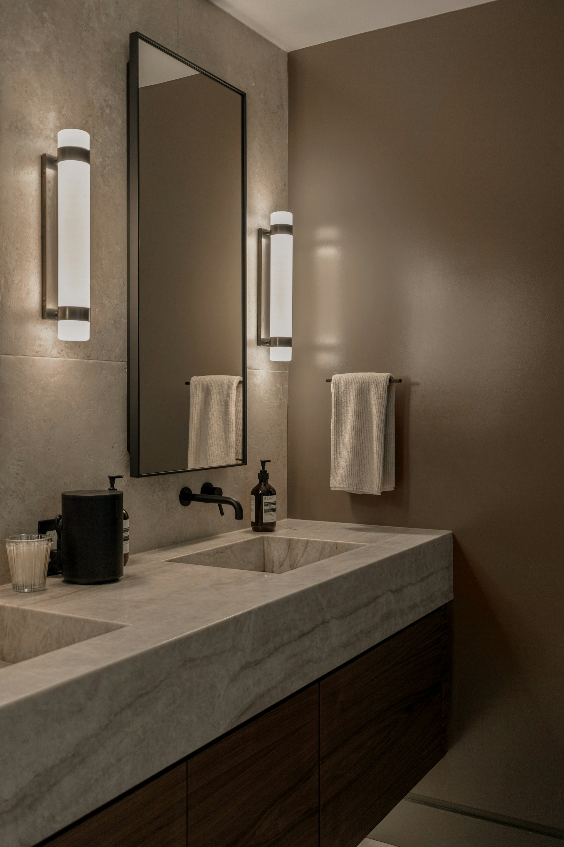 Modern bathroom vanity with double sinks and wall sconces.