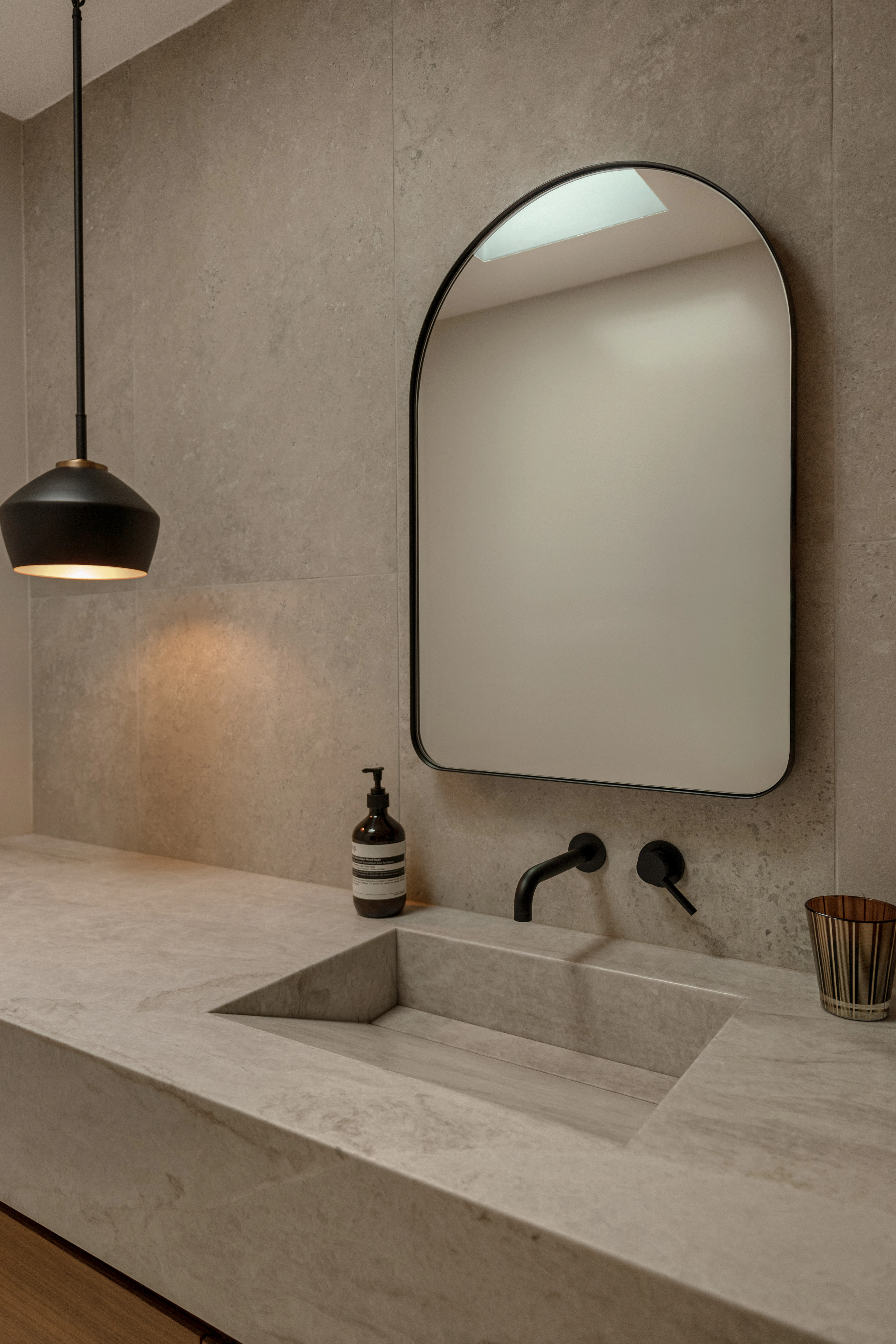 Modern bathroom with concrete sink and arched mirror
