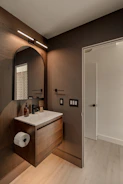 Modern bathroom with wooden vanity and arched mirror.