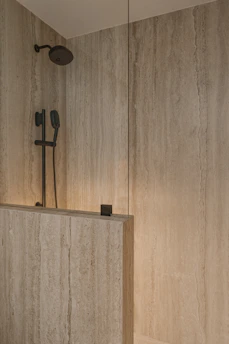 Modern shower with travertine tile and black fixtures in Phoenix, Az.