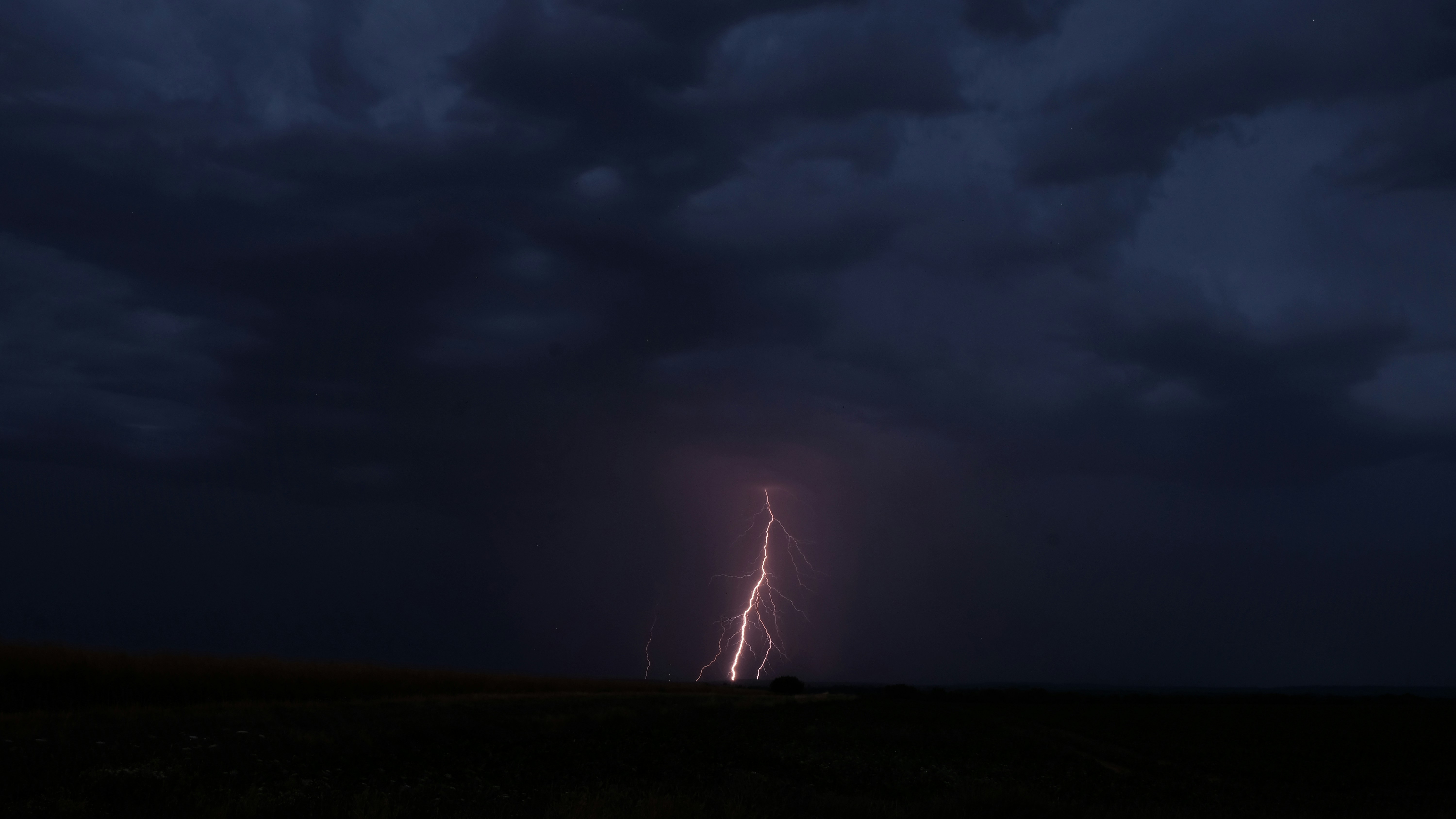 Lightning strikes the ground during a dark storm.