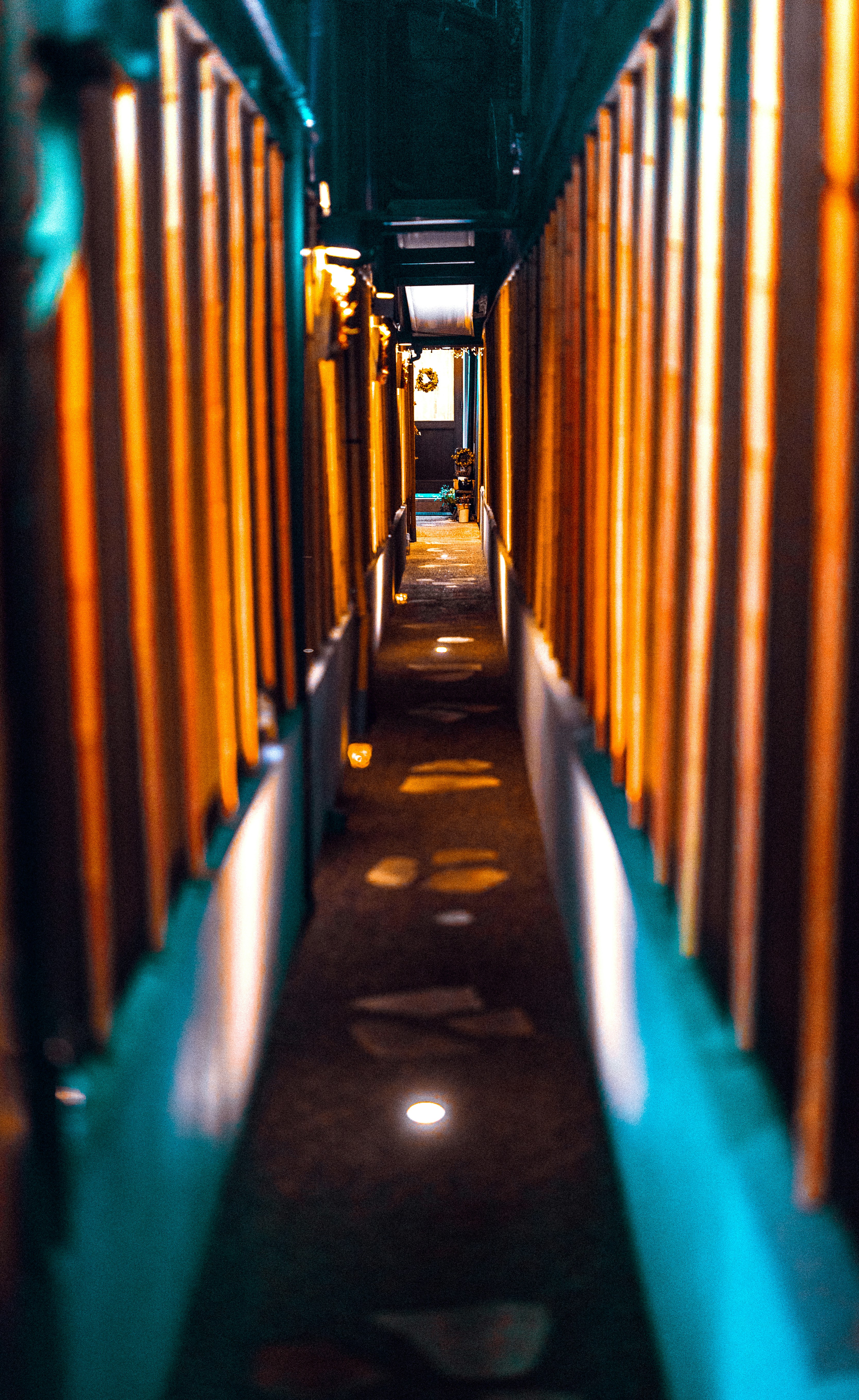 Narrow hallway with wooden walls and floor lights.