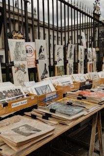 Art and books displayed for sale along a fence