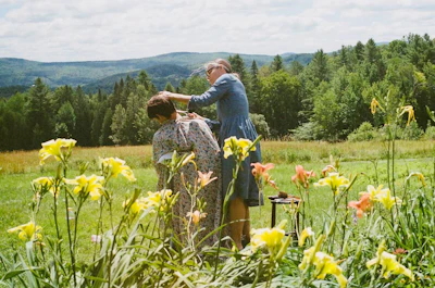Two women in a meadow with flowers and trees
